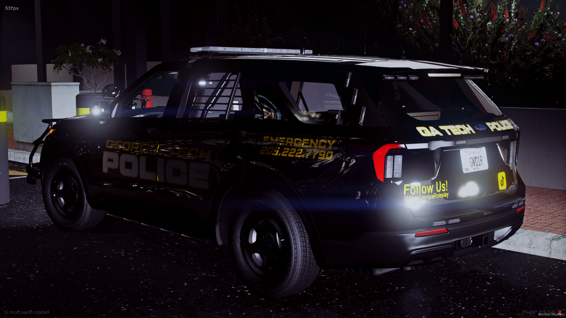 Black Georgia Tech police SUV parked at night with emergency lights on, featuring decals with contact info, social media handles, and a message encouraging following the department on social media.