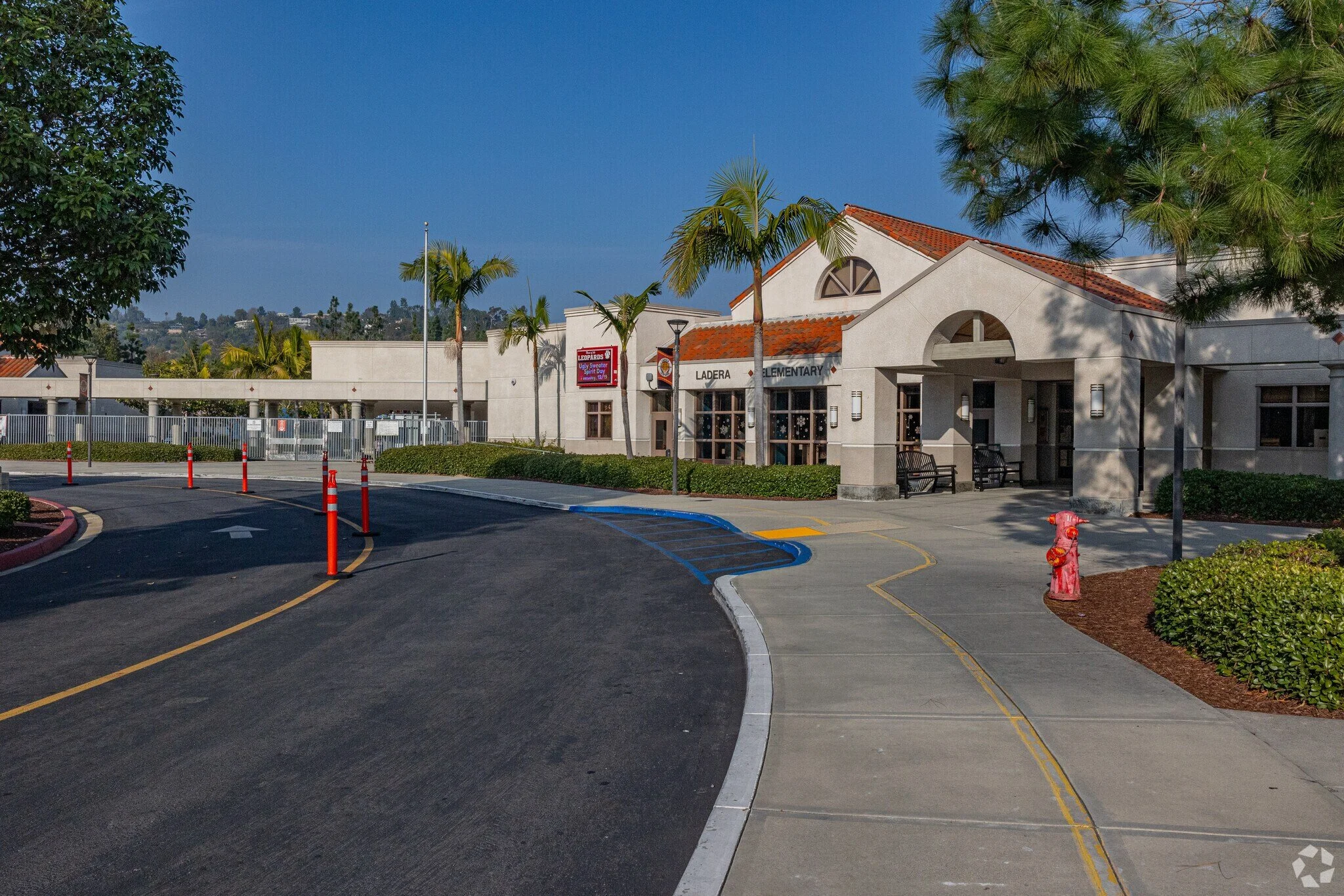 Exterior view of Ladera Elementary School building with palm trees and a clear blue sky.