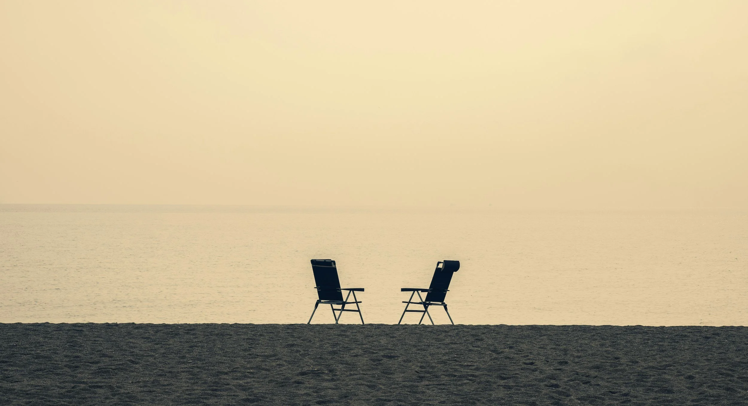 Couples therapy in San Diego. Two empty chairs facing each other on a beach.