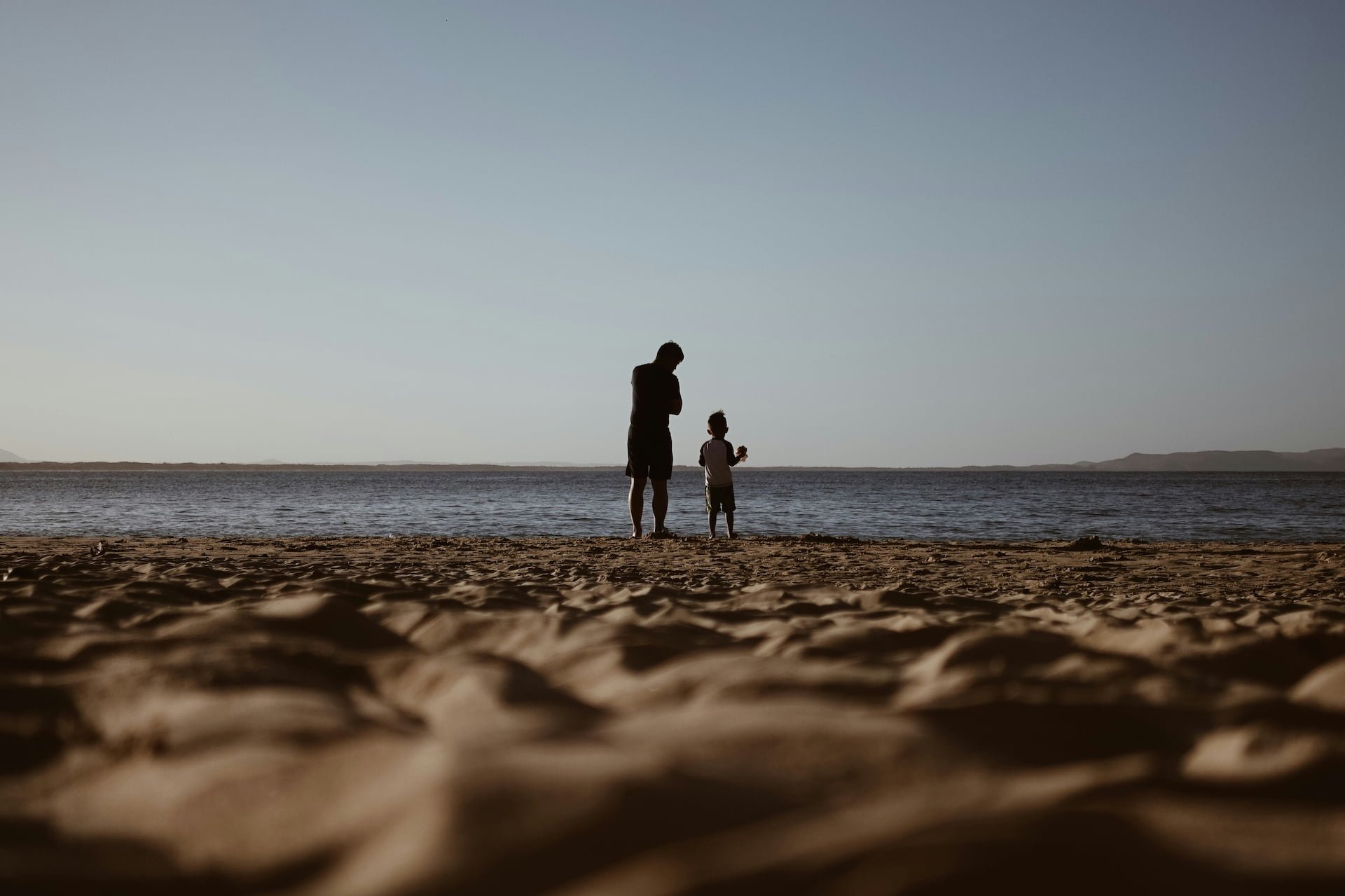 dad and child at the beach looking at ocean