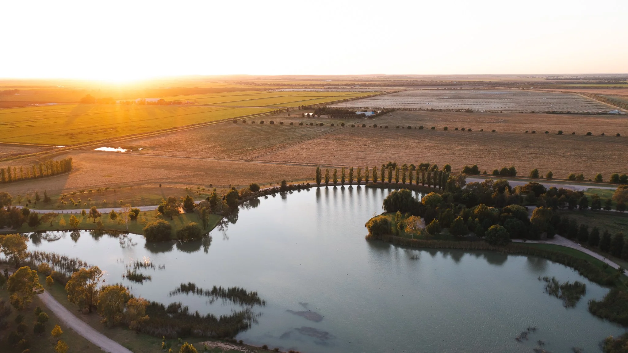 Sunset over a rural landscape with a large pond, trees, fields, and farmland, drone, property, New South Wales, Australia.