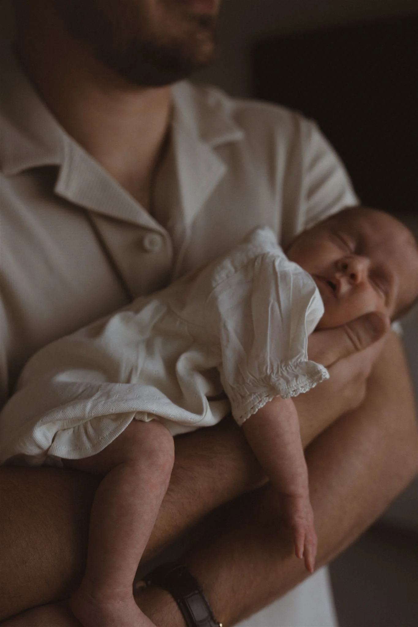 An adult holding a sleeping newborn baby in their arms.