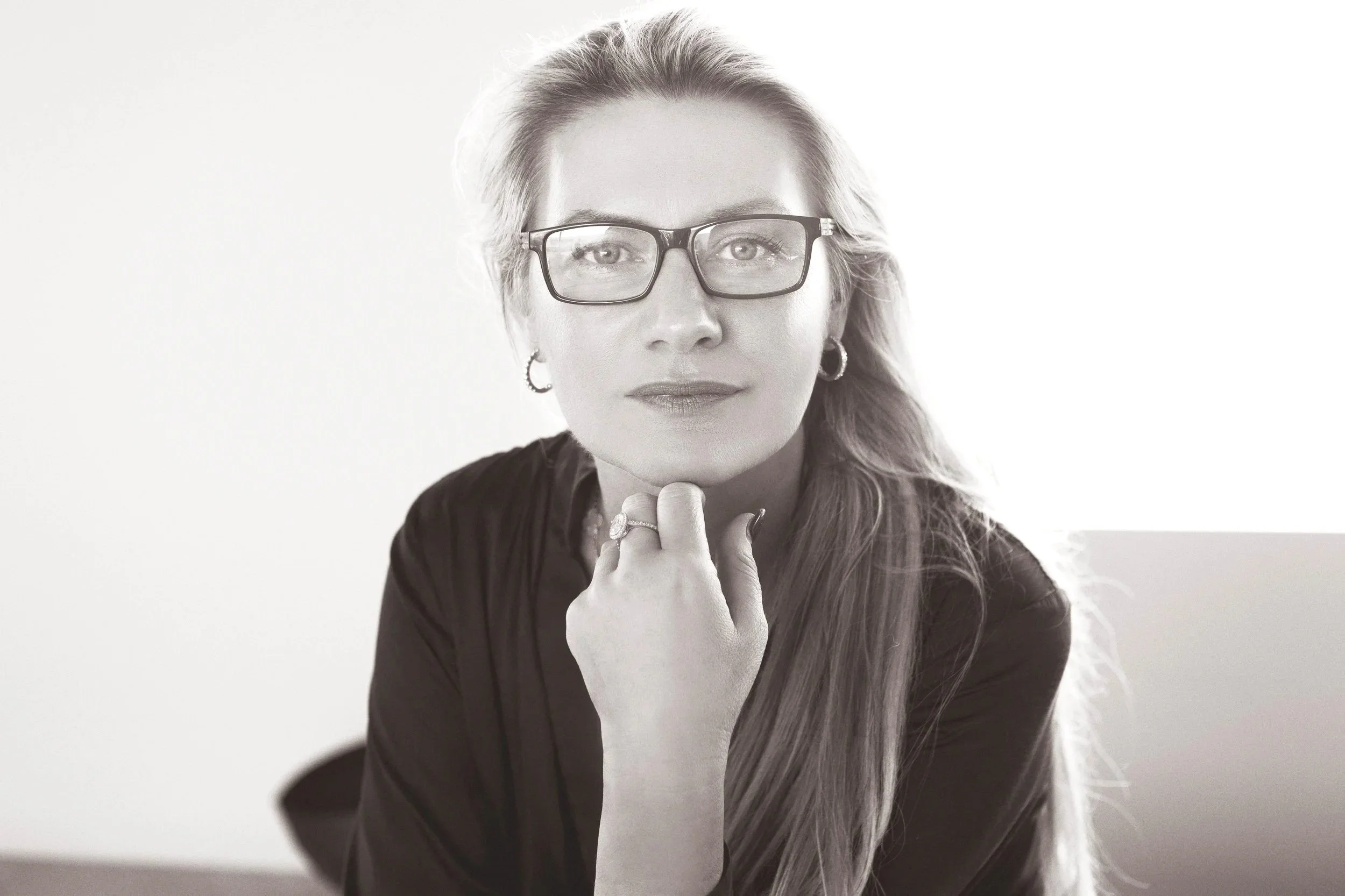 Lisa resting her chin on her hand, looking at the camera in a black and white portrait.