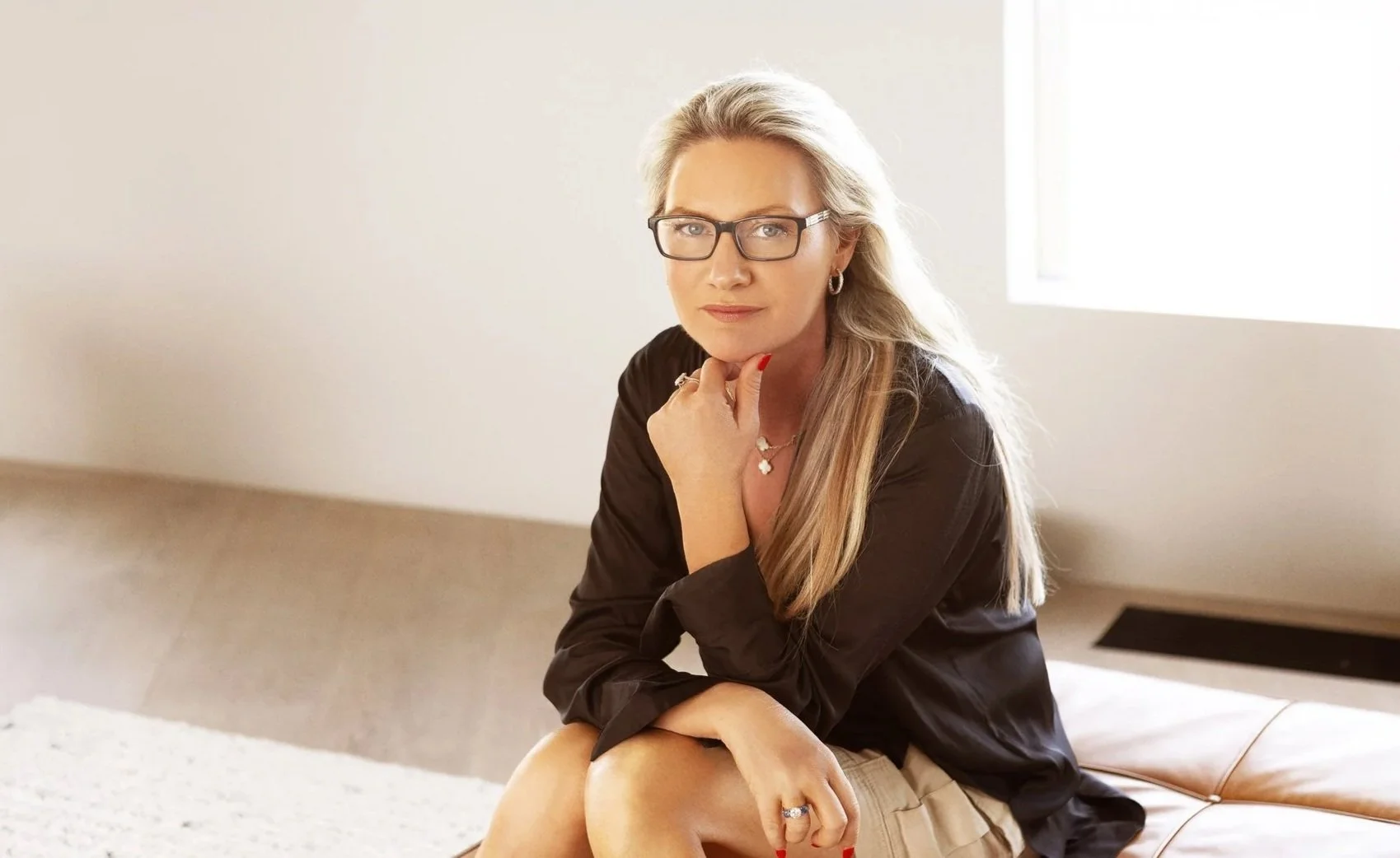 Portrait of Lisa sitting on a bench in a well-lit room with a neutral-colored wall behind her.