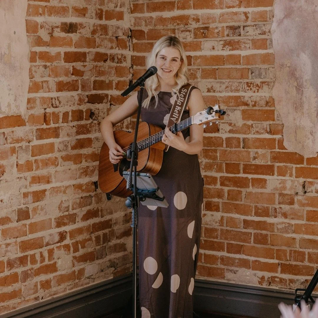 Stella Kelly singing and playing guitar at a wedding ceremony at Guildford Hall