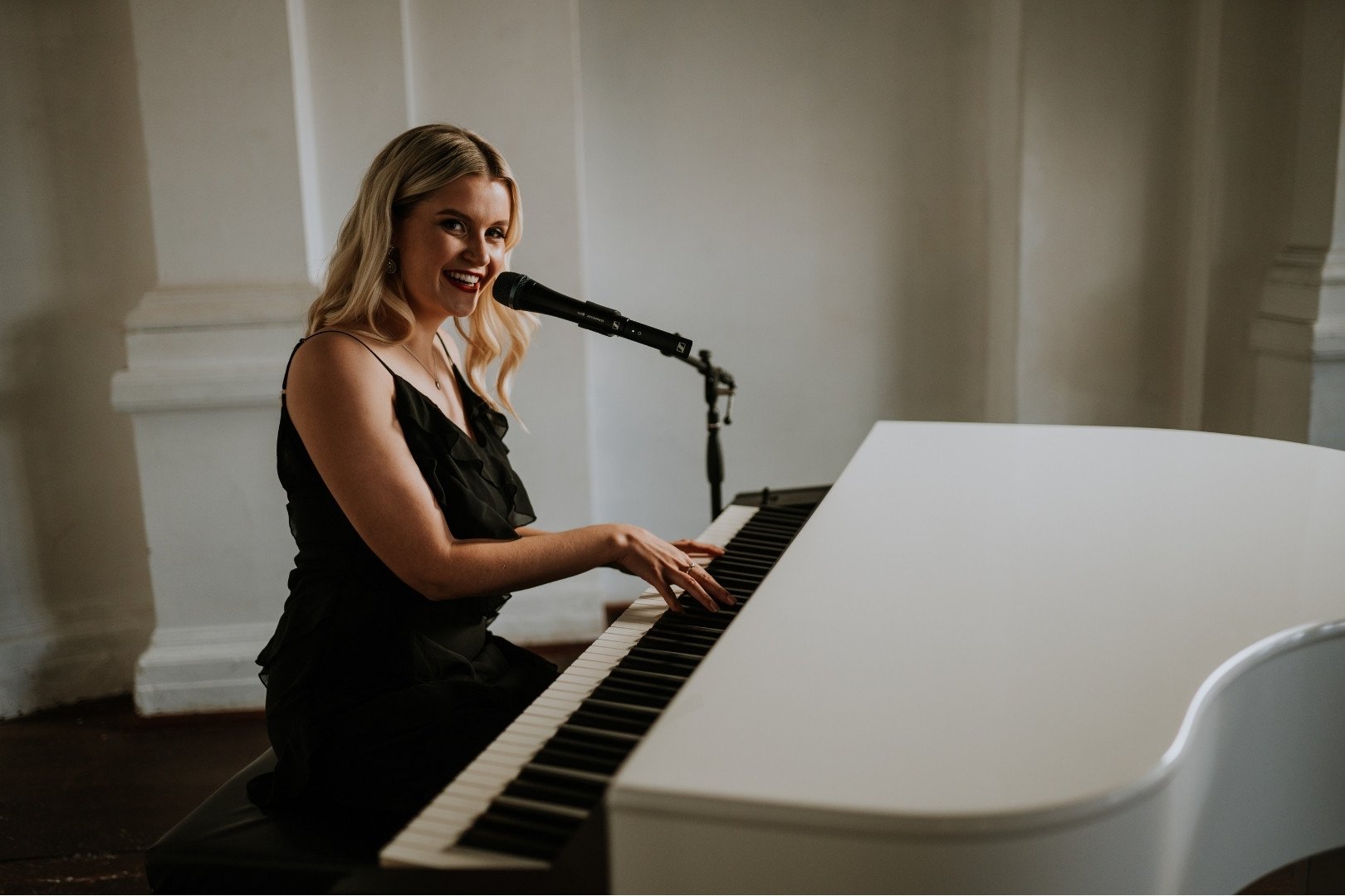 Stella Kelly singing and playing piano on a grand piano at moana hall