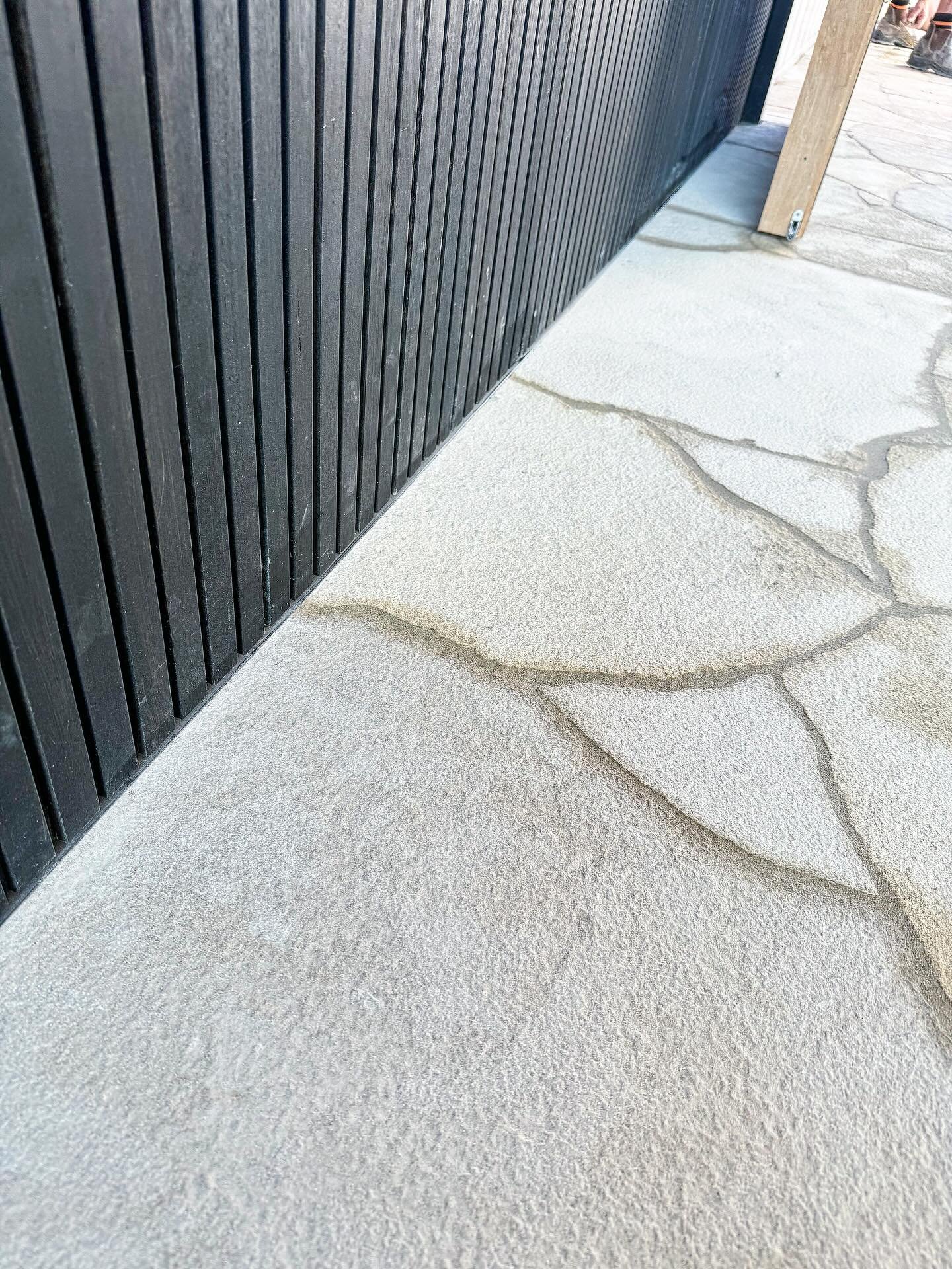 Clean lines meet natural texture - crazy paving detail completed for @forster_constructions in Red Hill. The perfect tone against the dark cladding 🤌🏼 #landscaping #hardscape #crazypaving #landscapestyles