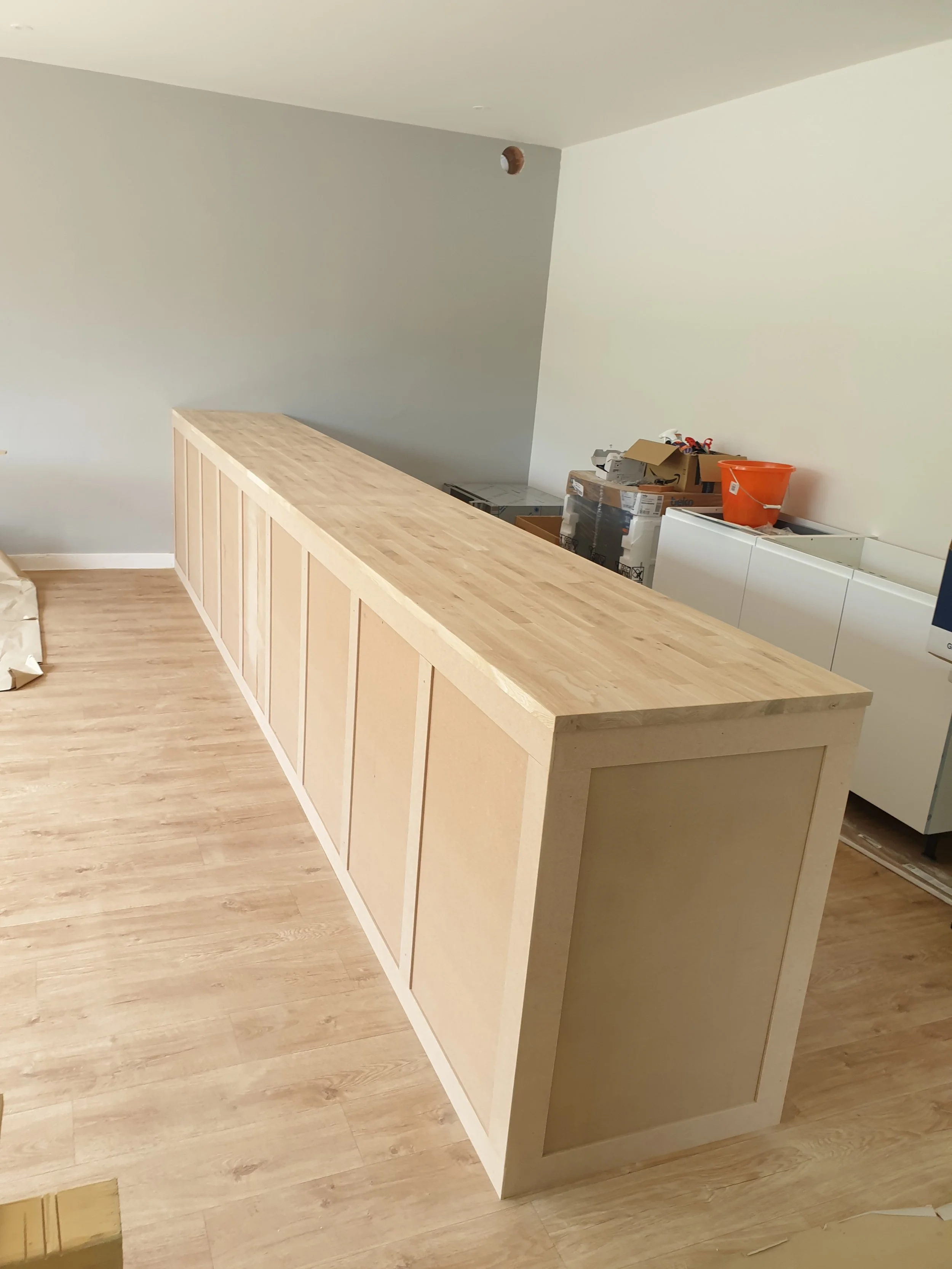 Photo of a partially built wooden bar or counter in a room under construction or renovation.