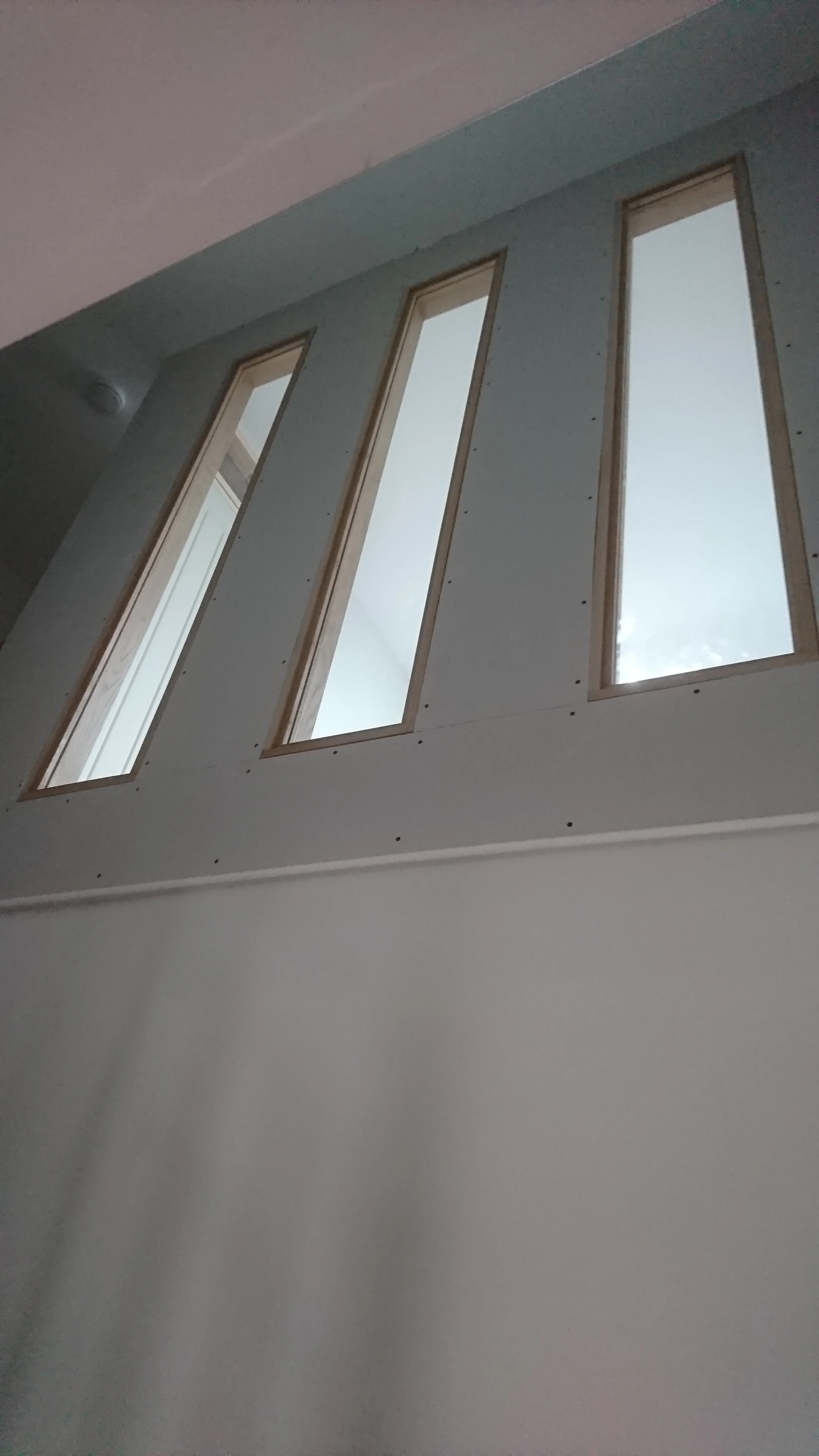Interior wall with four narrow rectangular windows during building or remodeling.