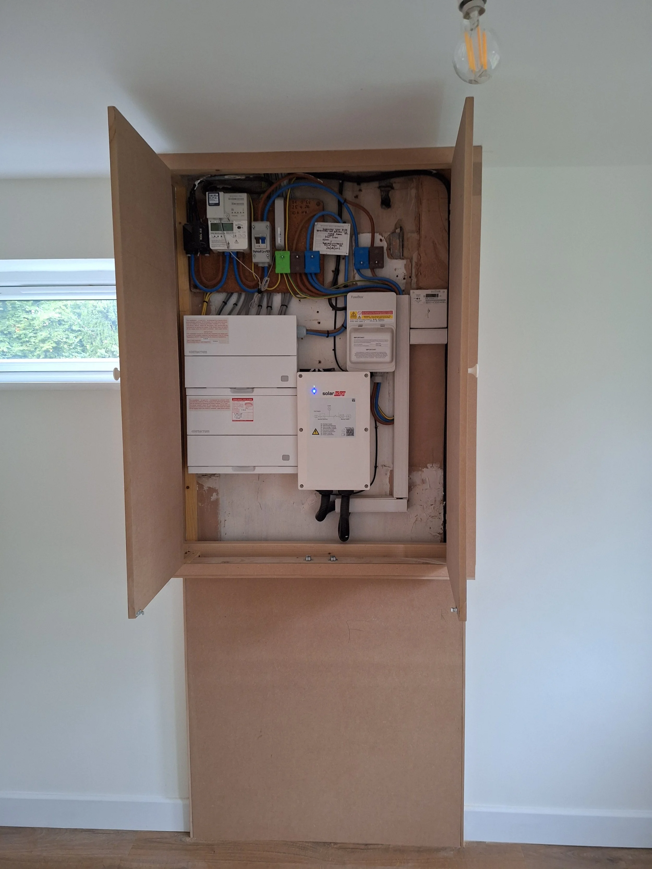 An electrical panel with wires and circuit breakers inside a wooden frame.