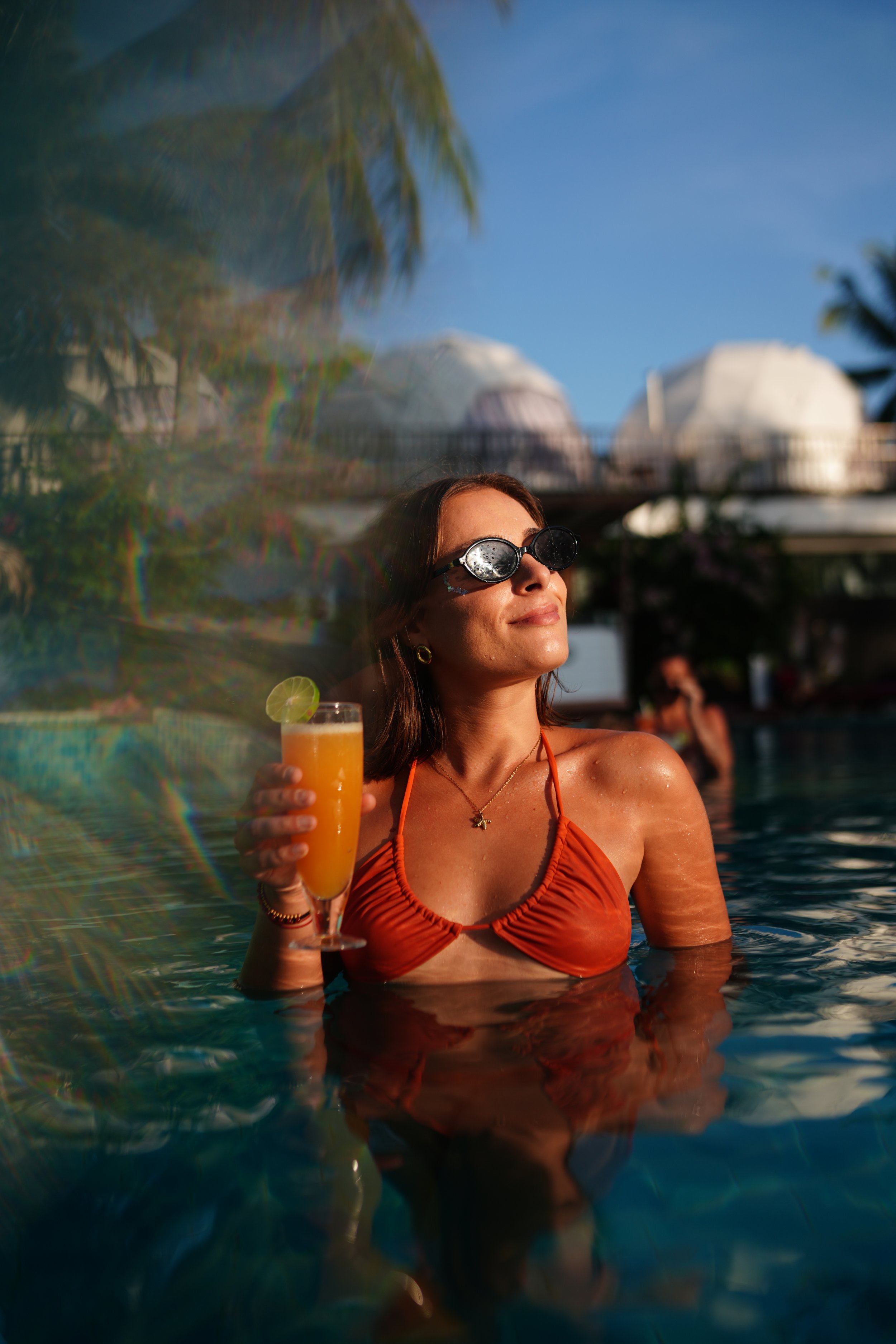 A woman  on the pool drinking a cocktel in a bikini 