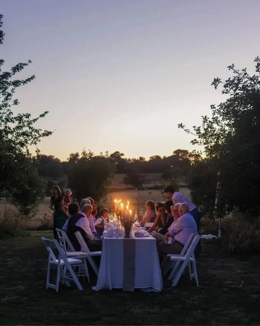 Dineren aan lange tafels in de boomgaard met de ondergaande zon.