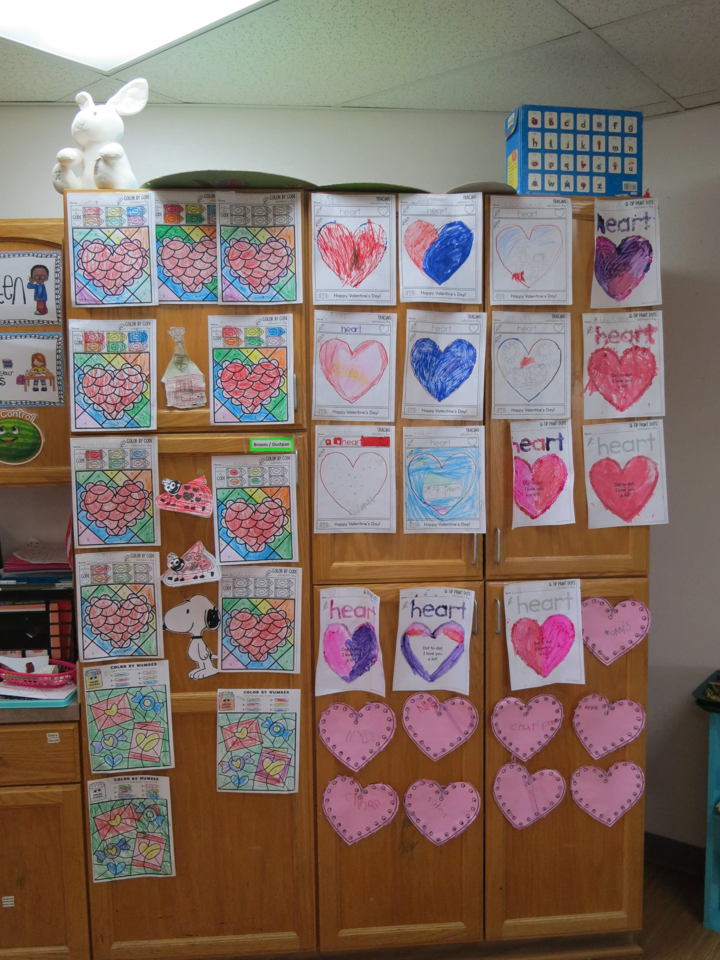 Children's artwork of colorful hearts, some with names or messages, displayed on a wooden cabinet in a classroom. (The Cross Schools of Education - Walnut, CA)