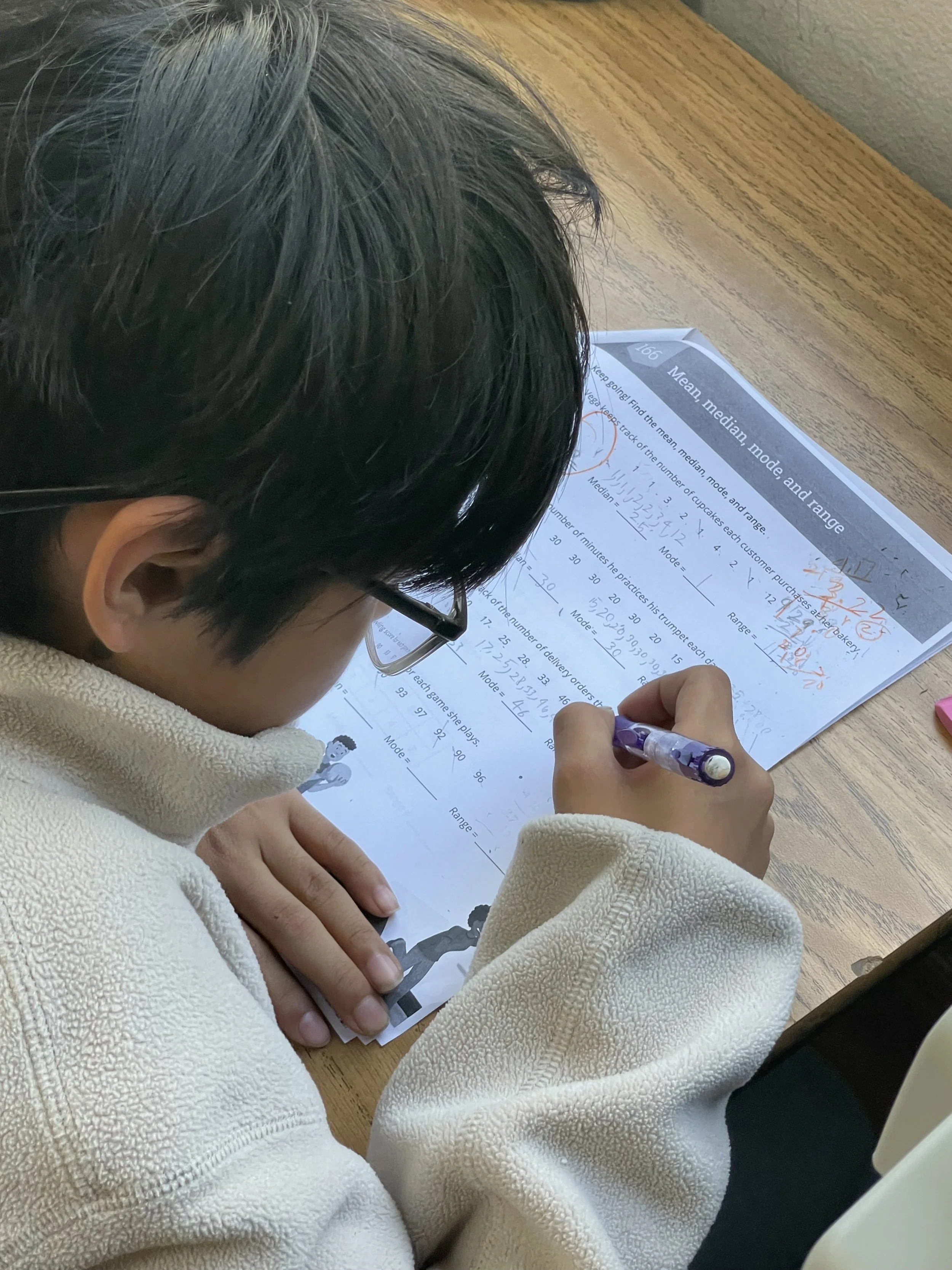 A 6th-grade boy in The Cross Schools of Education After-School program is completing math homework regarding mean, median, and mode in Walnut, CA.