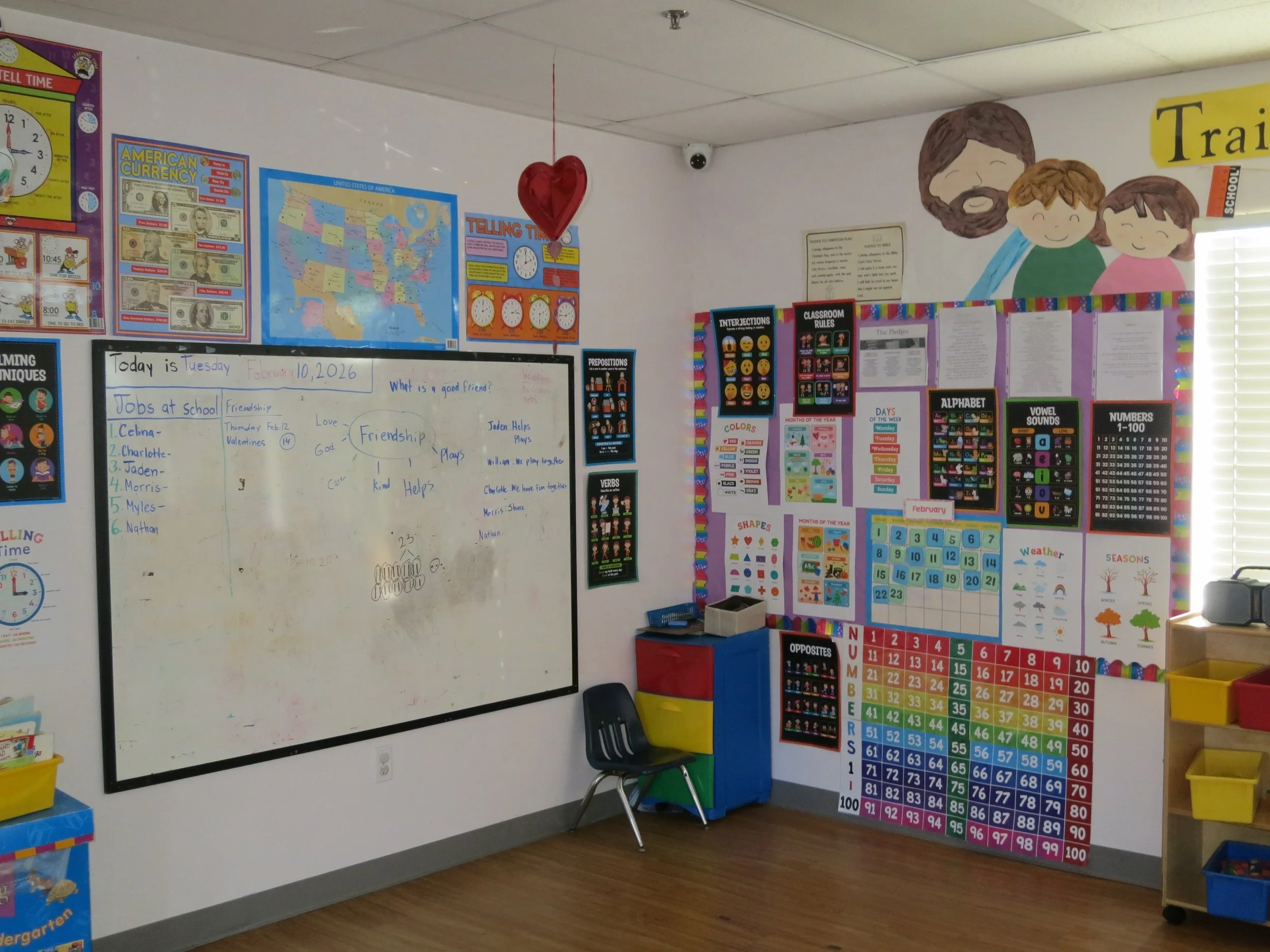 A preschool classroom with educational posters, a whiteboard with writing, and colorful decorations. (The Cross Schools of Education - Walnut, CA)