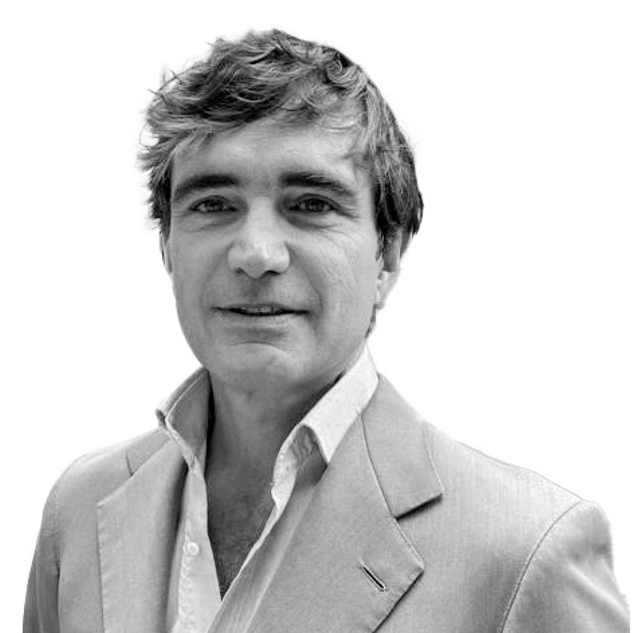 Black and white portrait of a man with wavy hair wearing a light-colored blazer and a collared shirt.