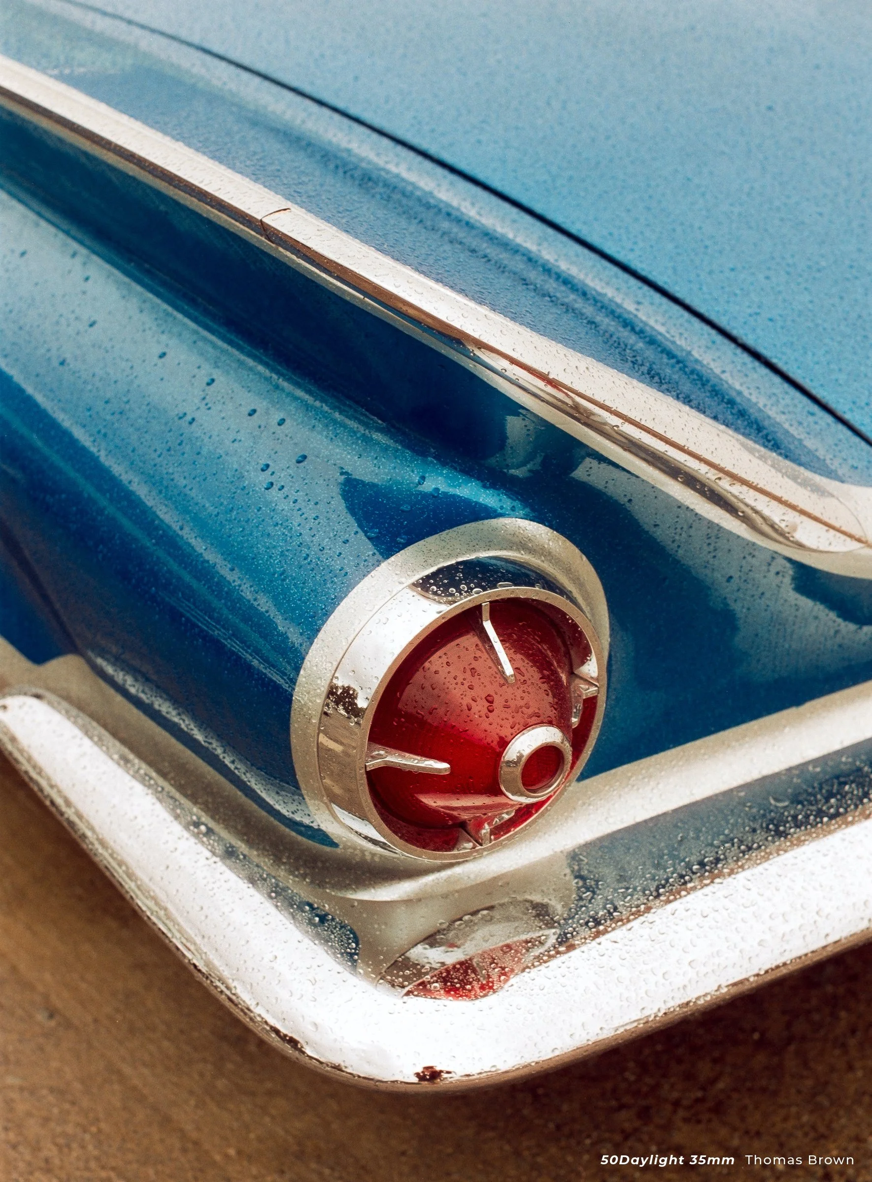 Cinestill 50D sample photo of a retro cars tail light. The car has rain droplets on it.