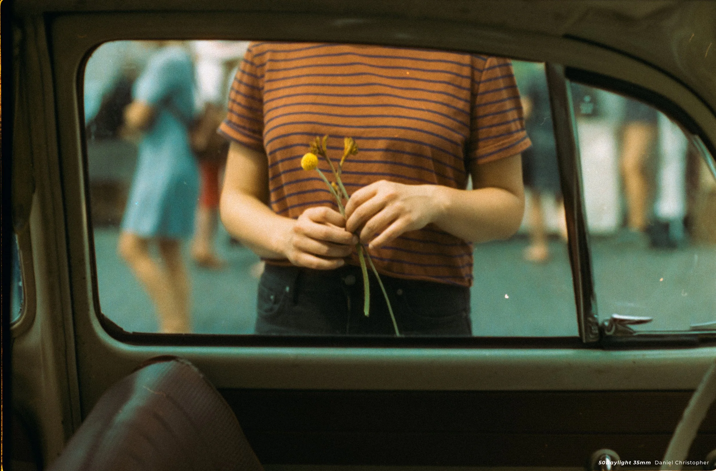 cinestill 50D sample photo of woman holding flowers shot from inside car looking out