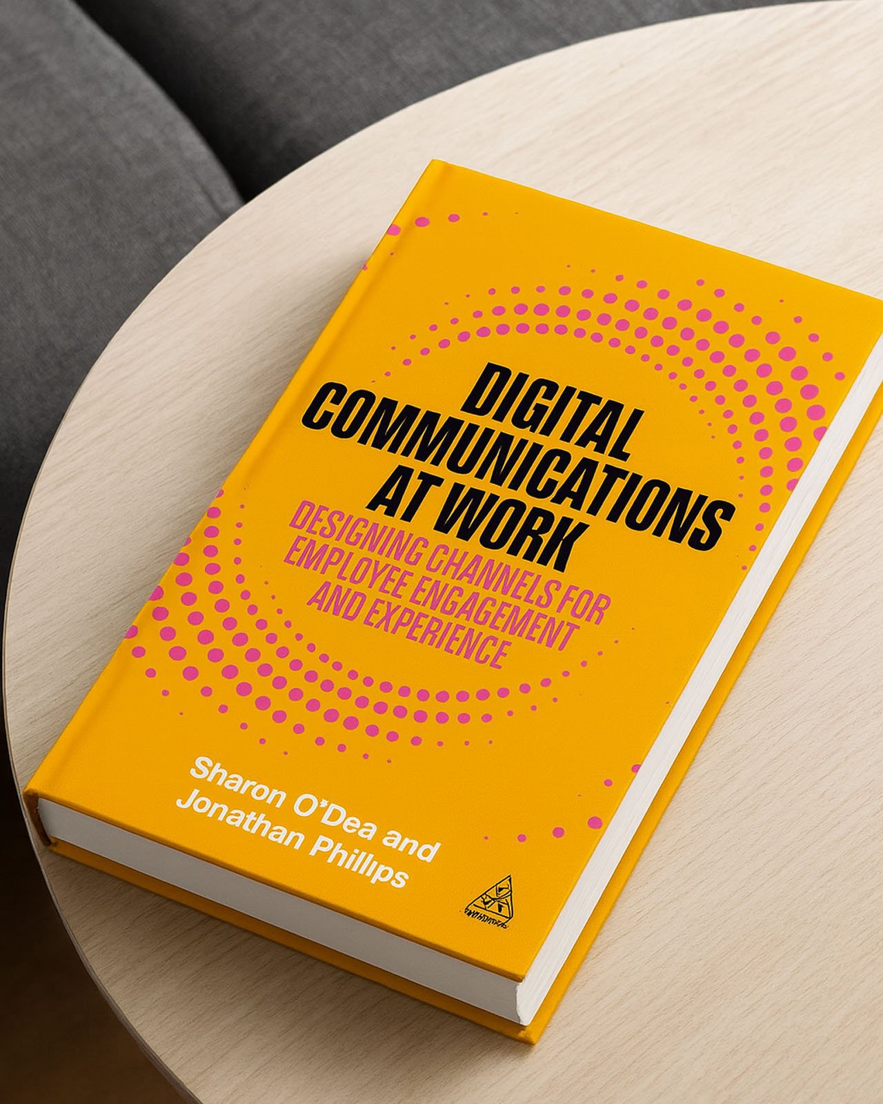 A book titled 'Digital Communications at Work' with a yellow cover and pink dot patterns, resting on a white round table.