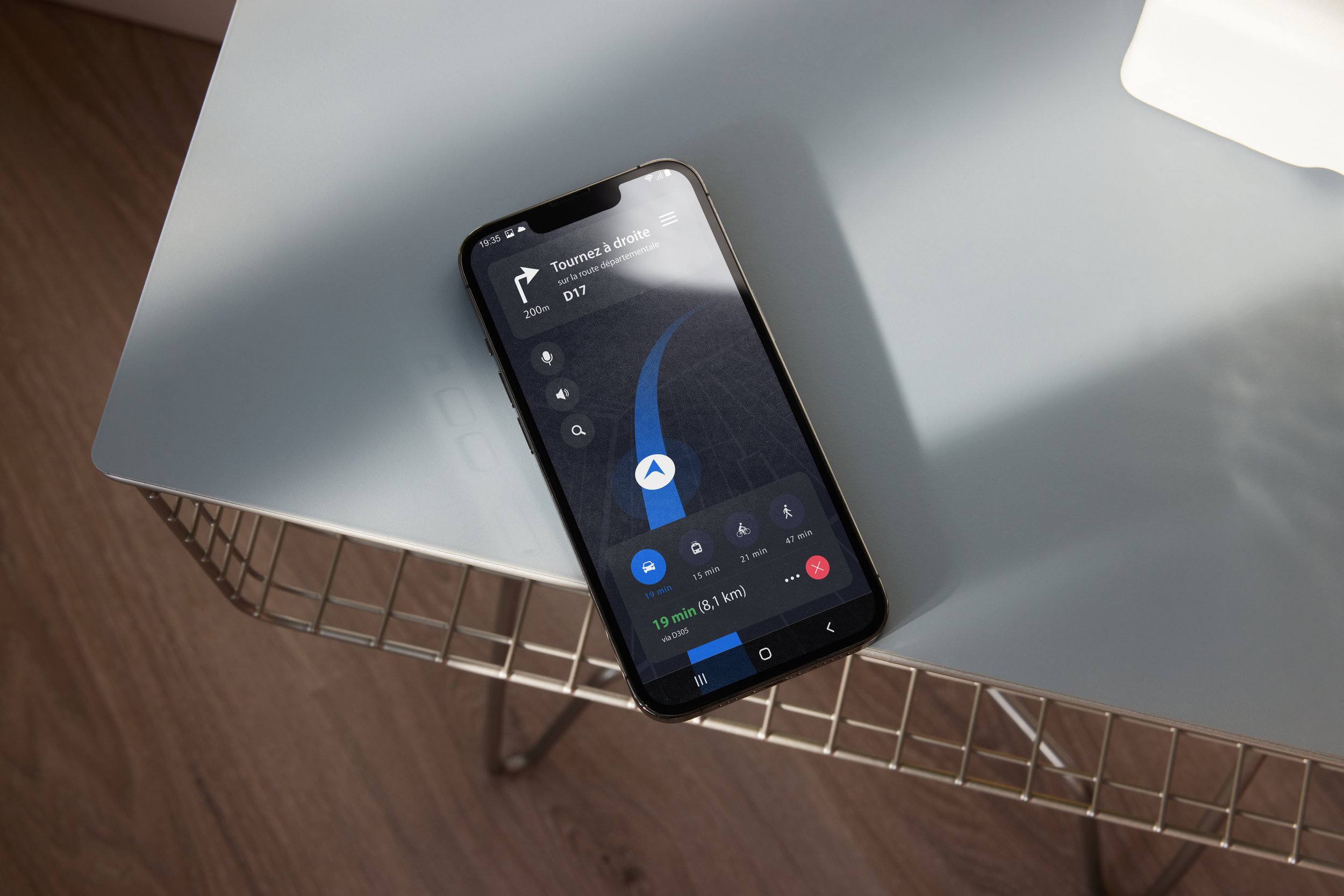Smartphone affichant une application de navigation, posé sur une table grise.