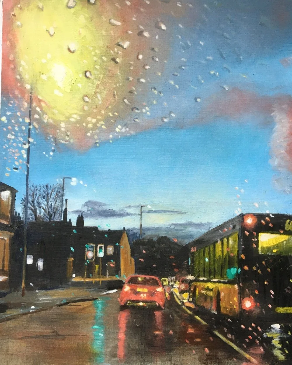Rainy evening street scene with reflections on the wet road, a red car ahead, a bus to the right, and glowing streetlights against a yellow‑to‑blue sky.