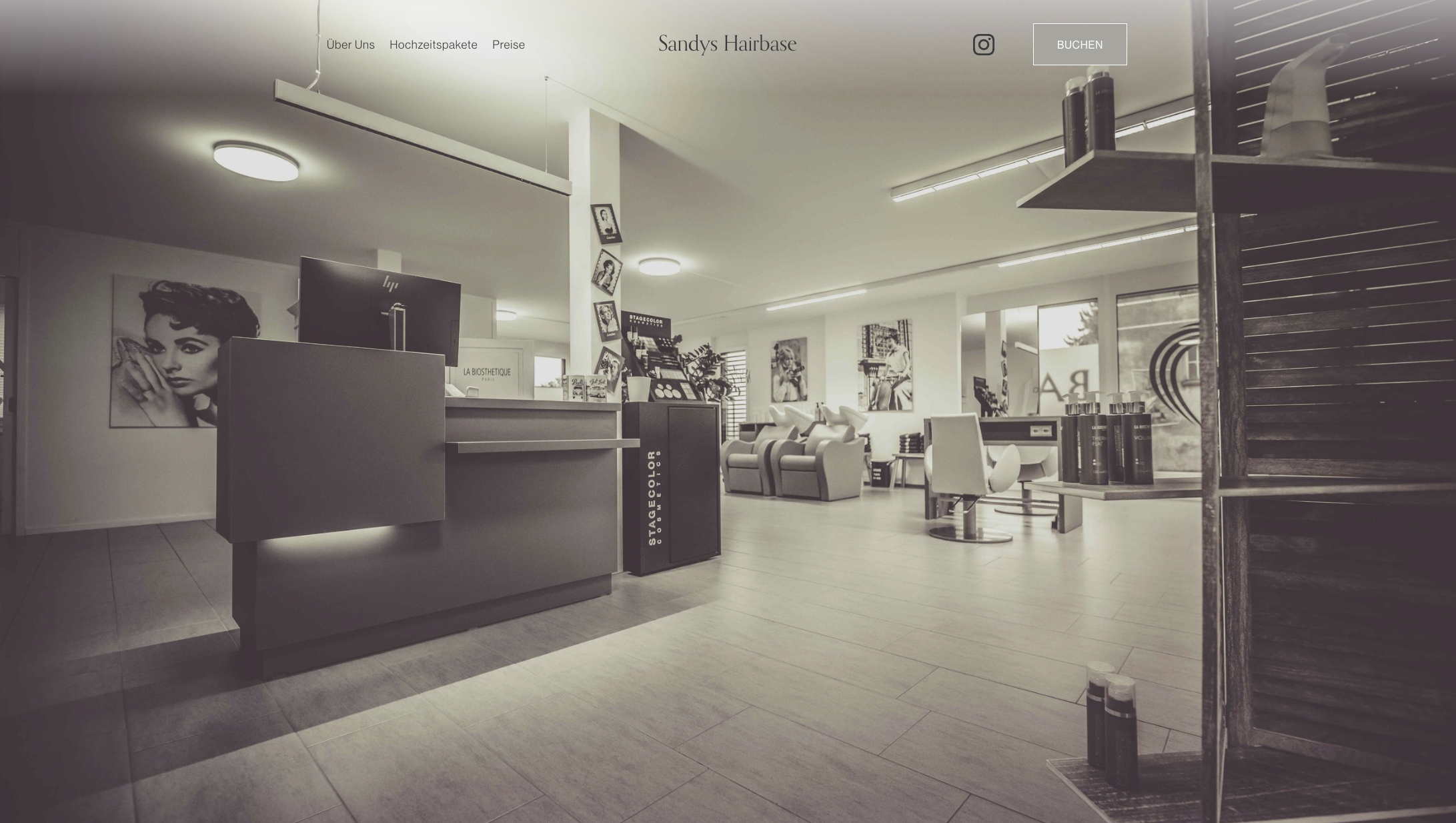 Innenansicht eines Friseursalons mit Empfangstheke, Haarprodukten, Sitzbereichen mit Friseurstühlen und Kunstfotografien an den Wänden.