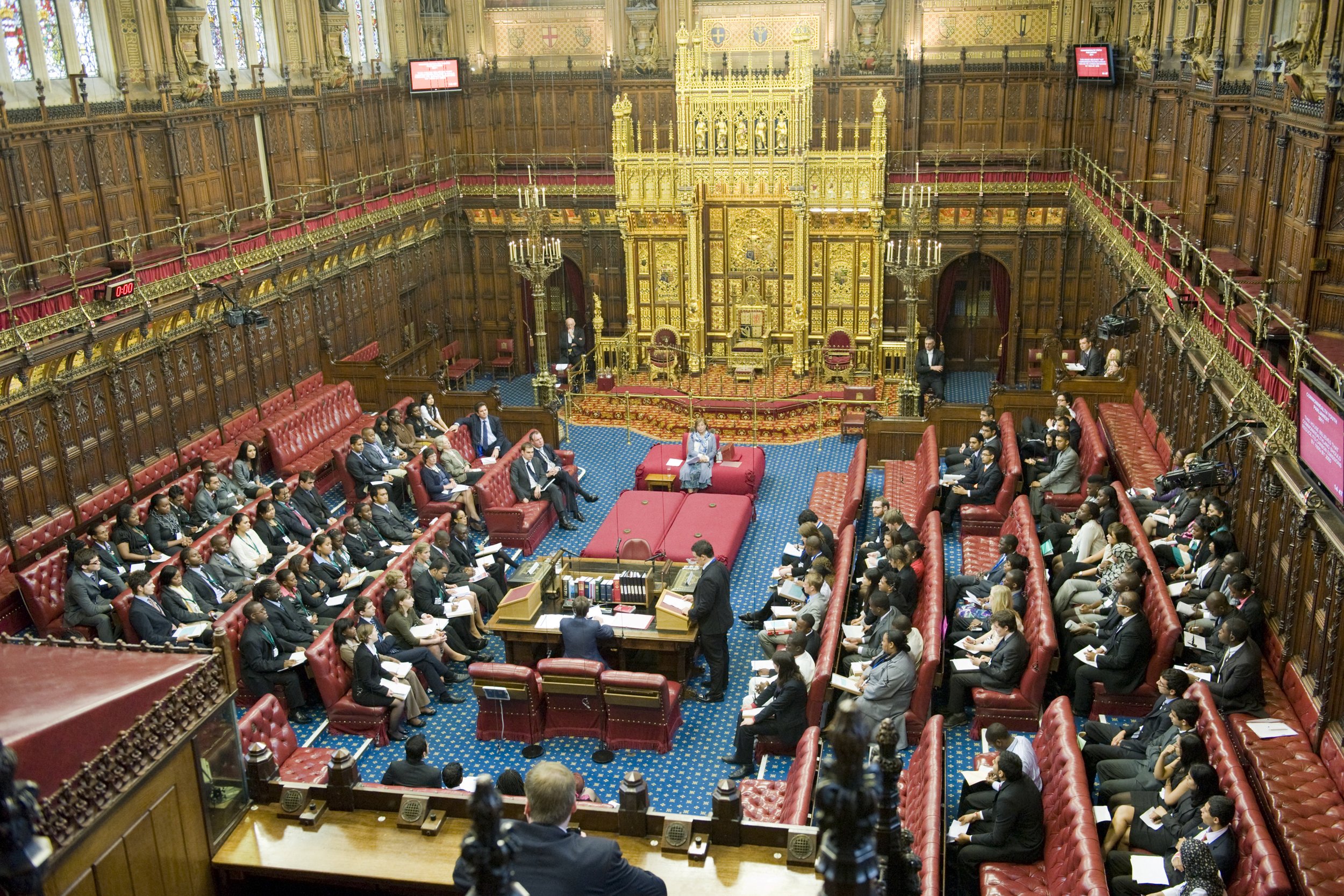 Image taken from wikimedia of the House of Lords interior chamber with people sitting and speaking