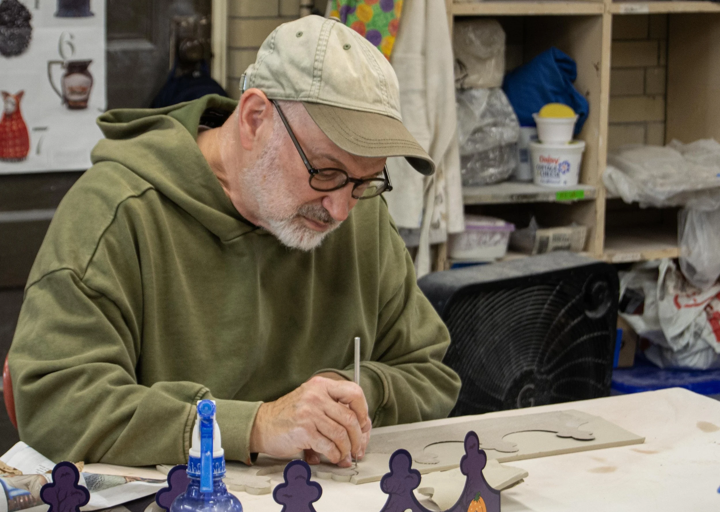 Jay Blumenfeld,  a photographer and greeting card maker who is also Deaf, traces a crown template onto a slab of clay during class on Wednesday, Nov. 4, 2025.