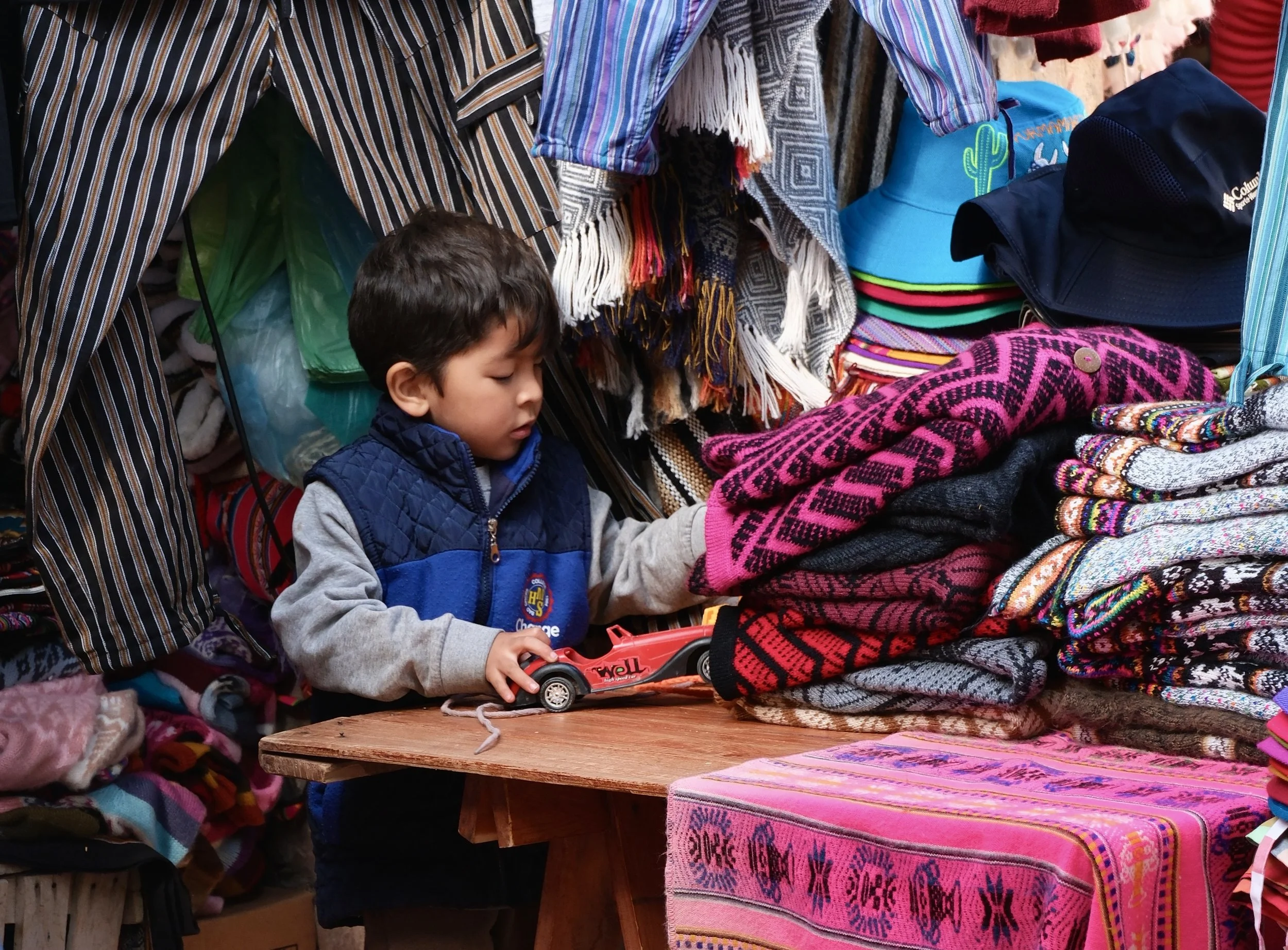 Among the textile and clothing stalls in the neighborhood market of Tilcara, Argentina, a young boy plays with his racecar toy on Jan. 9, 2026. 