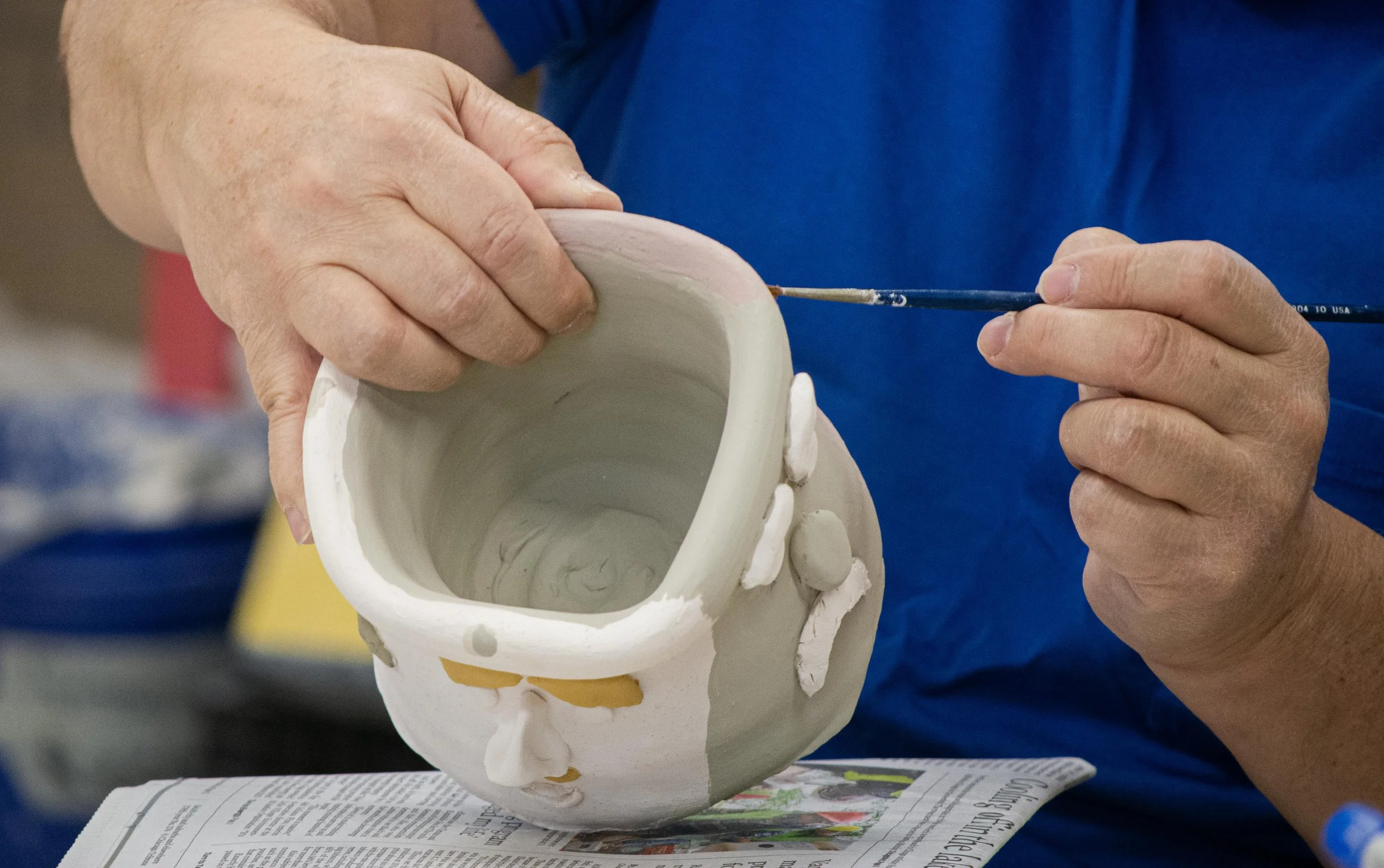 Herminio Cardona Jr., who is hard of hearing, carefully paints faces inspired by Picasso's artwork onto his mug on Wednesday, Nov. 4, 2025.