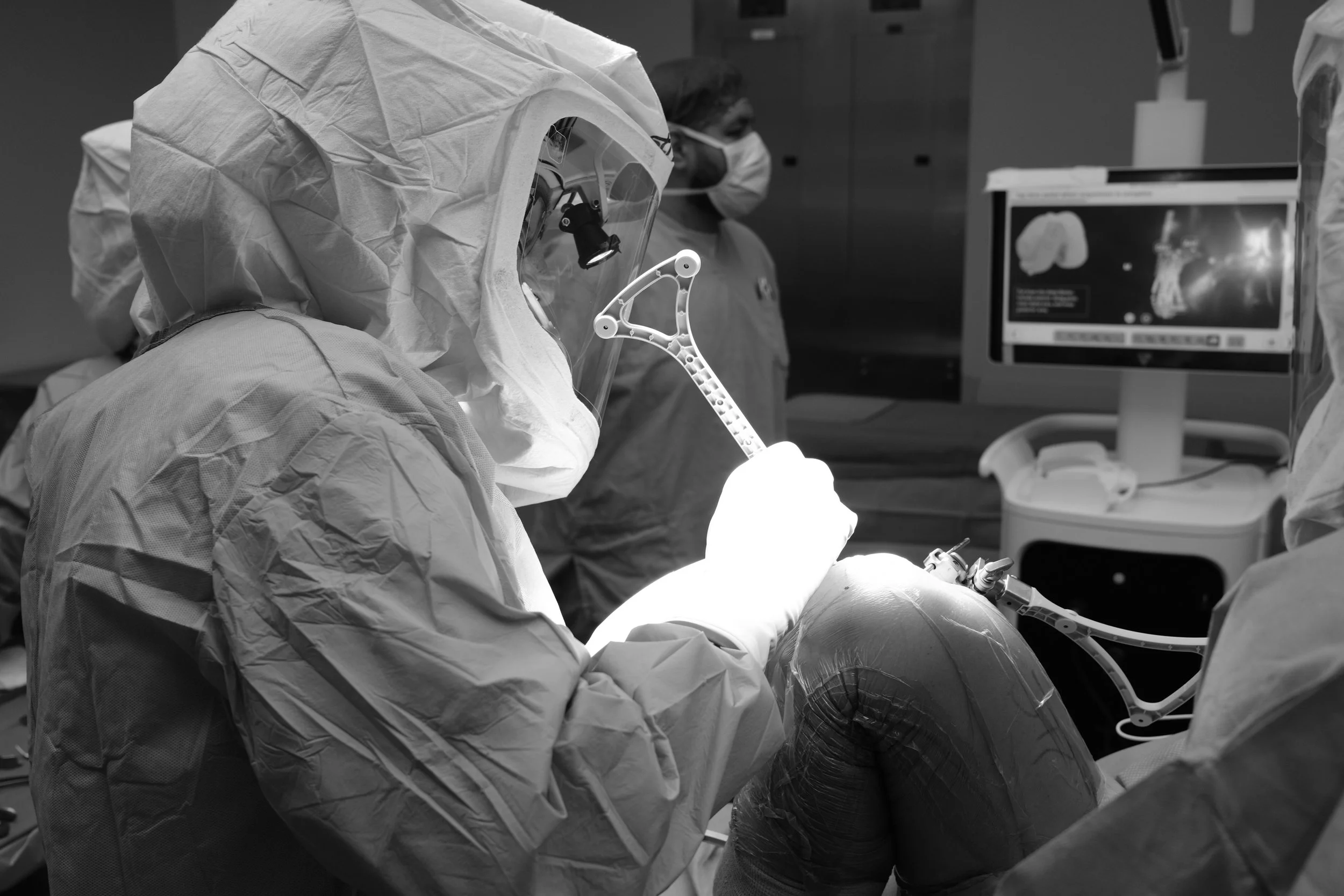 Orthopedic surgeon in protective performing robotic-assisted partial knee replacement.
