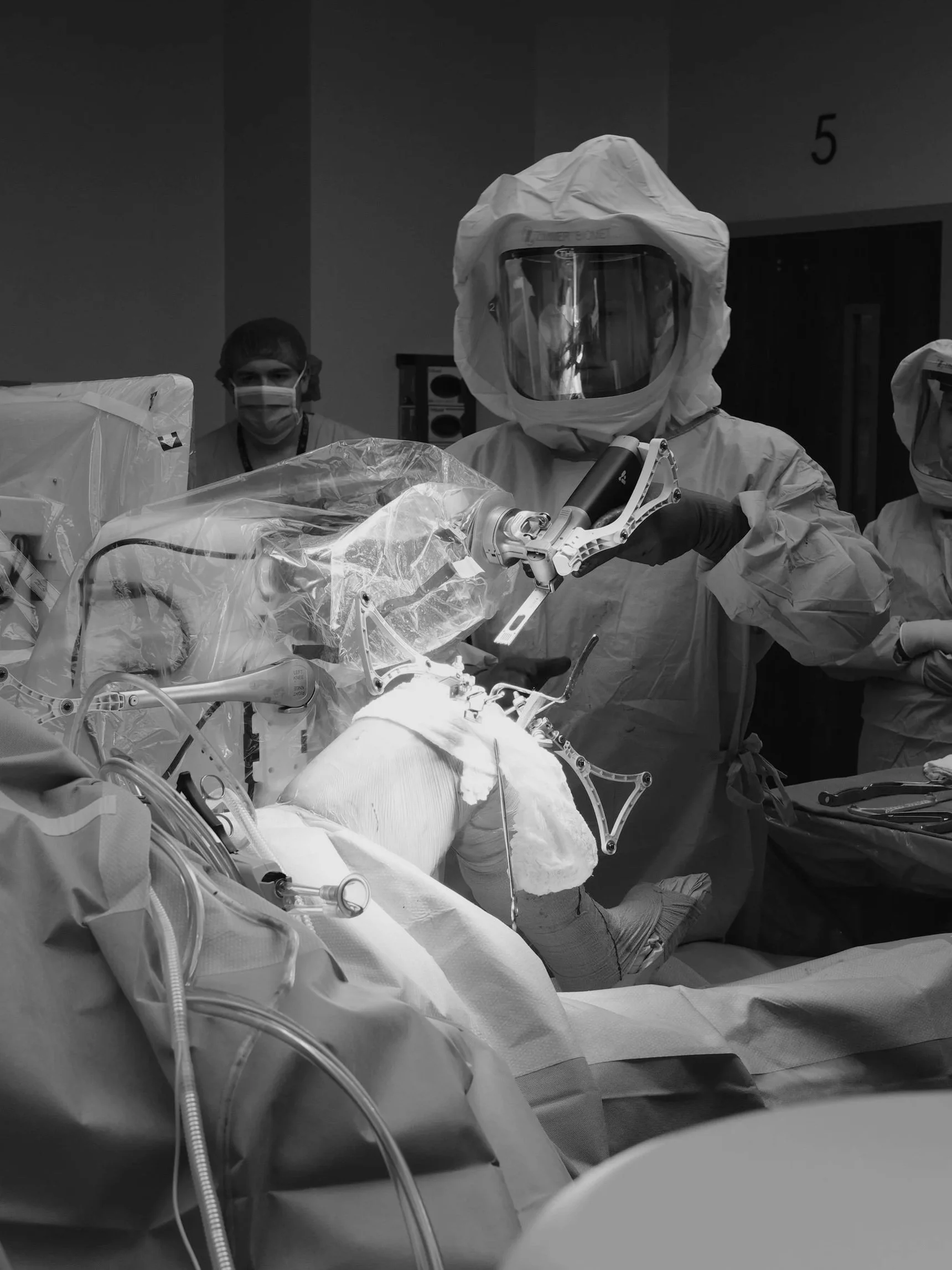 Surgeon performing robotic-assisted knee replacement surgery in a modern operating room.
