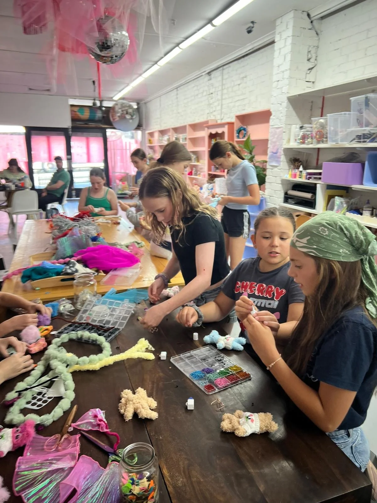 Group of tween girls in brigth colourful space making fluffy animals