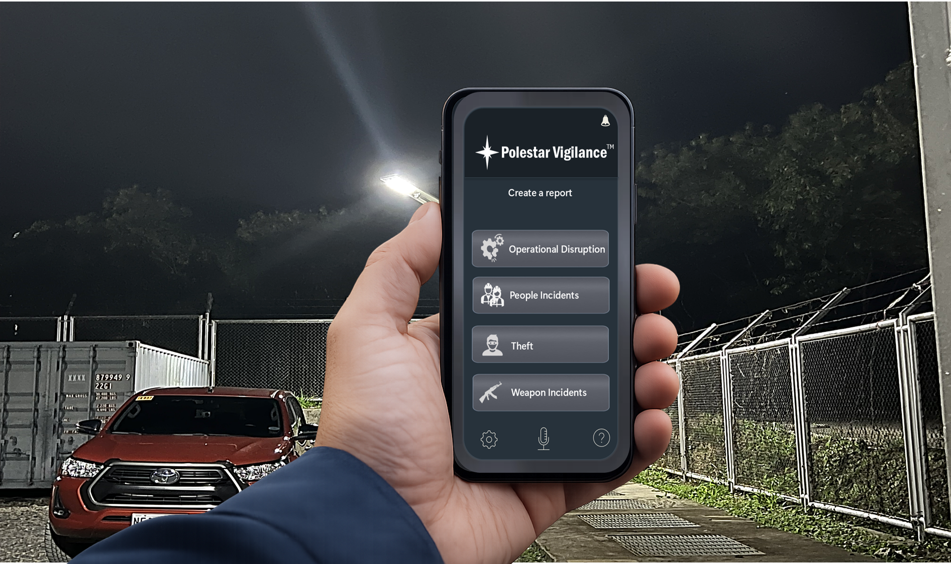 Person holding a smartphone with a security app open, displaying options for creating a report on operational disruption, people incidents, theft, and weapon incidents, outdoors at night near a red vehicle and a chain-link fence.