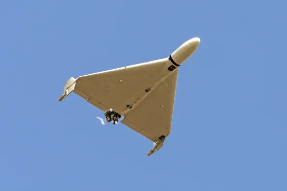 A sleek, white, unmanned aircraft flying in a clear blue sky.