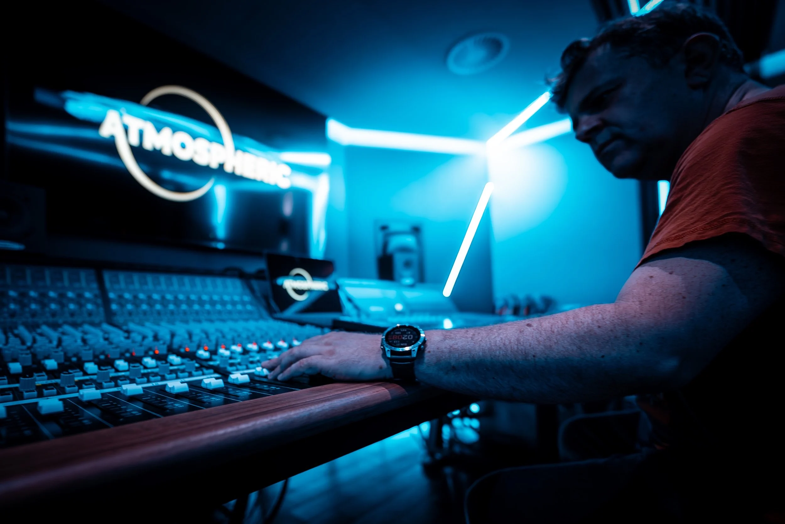 Founder, Patrick O'Luanaigh, is working in a music production studio at a mixing console with blue neon lighting around him.