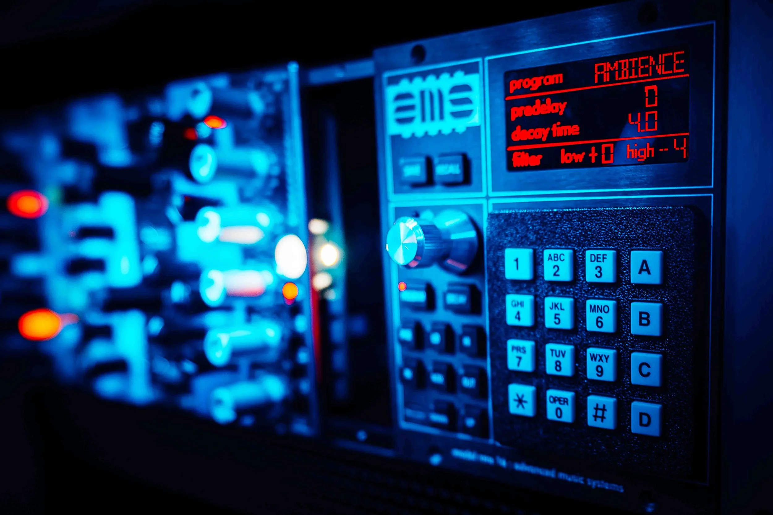 Close-up of electronic audio equipment with digital display and controls illuminated in blue and red lights.