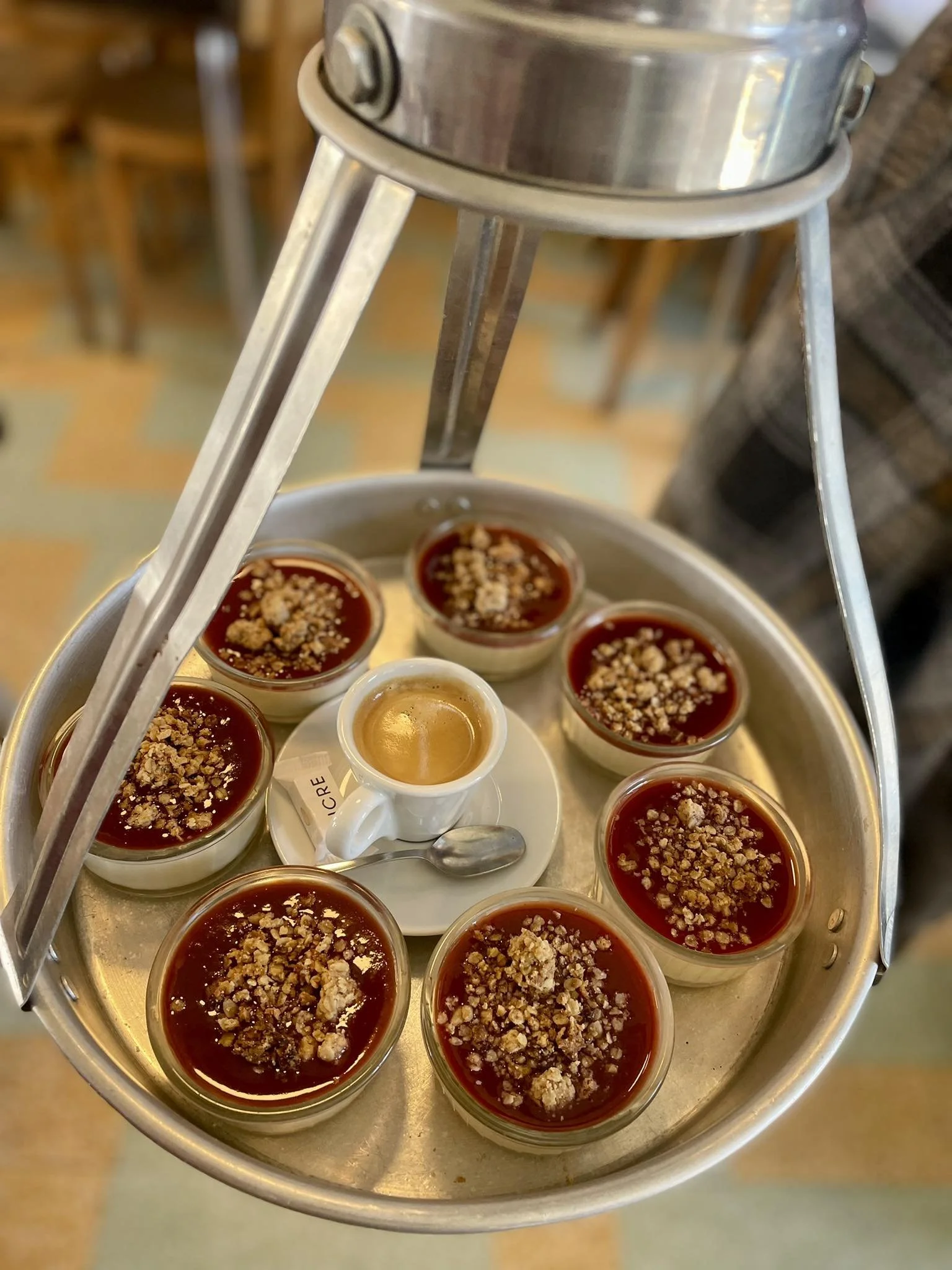 Assiette de desserts, dont des crèmes brûlées garnies de noisettes concassées, accompagnée d'une petite tasse de café.