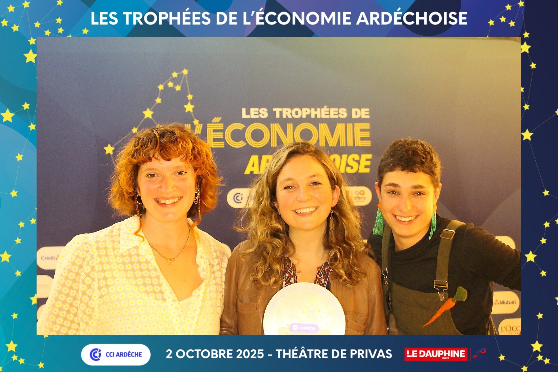 Trois femmes souriantes posant lors de la cérémonie de remise des trophées de l'économie ardéchoise, avec un fond bleu et des étoiles représentant la région d'Ardèche, à Privas, en octobre 2025.