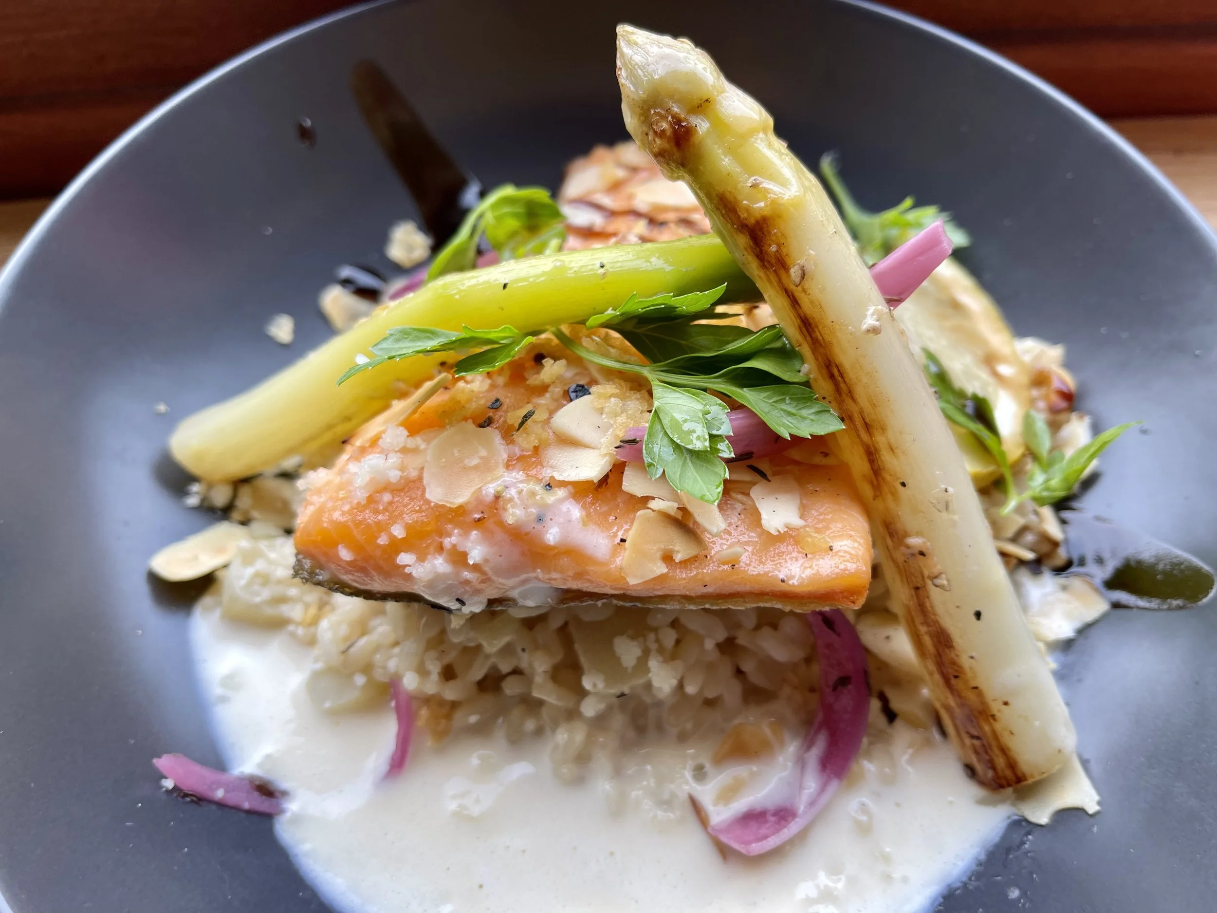 Assiette de saumon poché avec asperges, garnitures de légumes, herbes et sauce blanche.