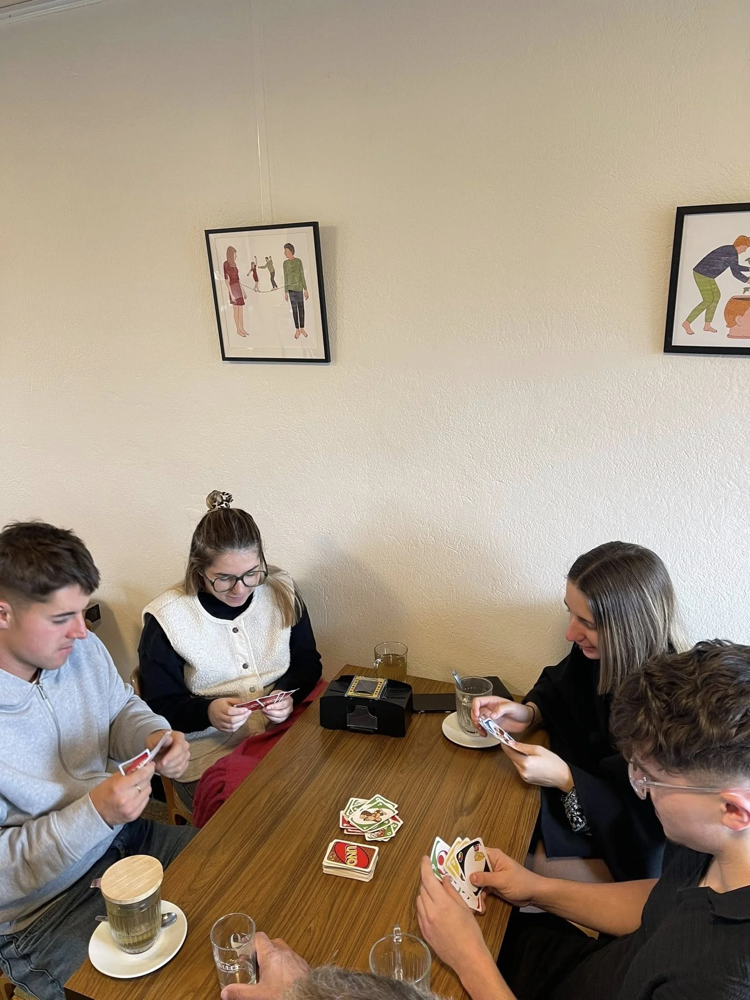 Groupe de jeunes jouant à un jeu de cartes autour d'une table dans un café