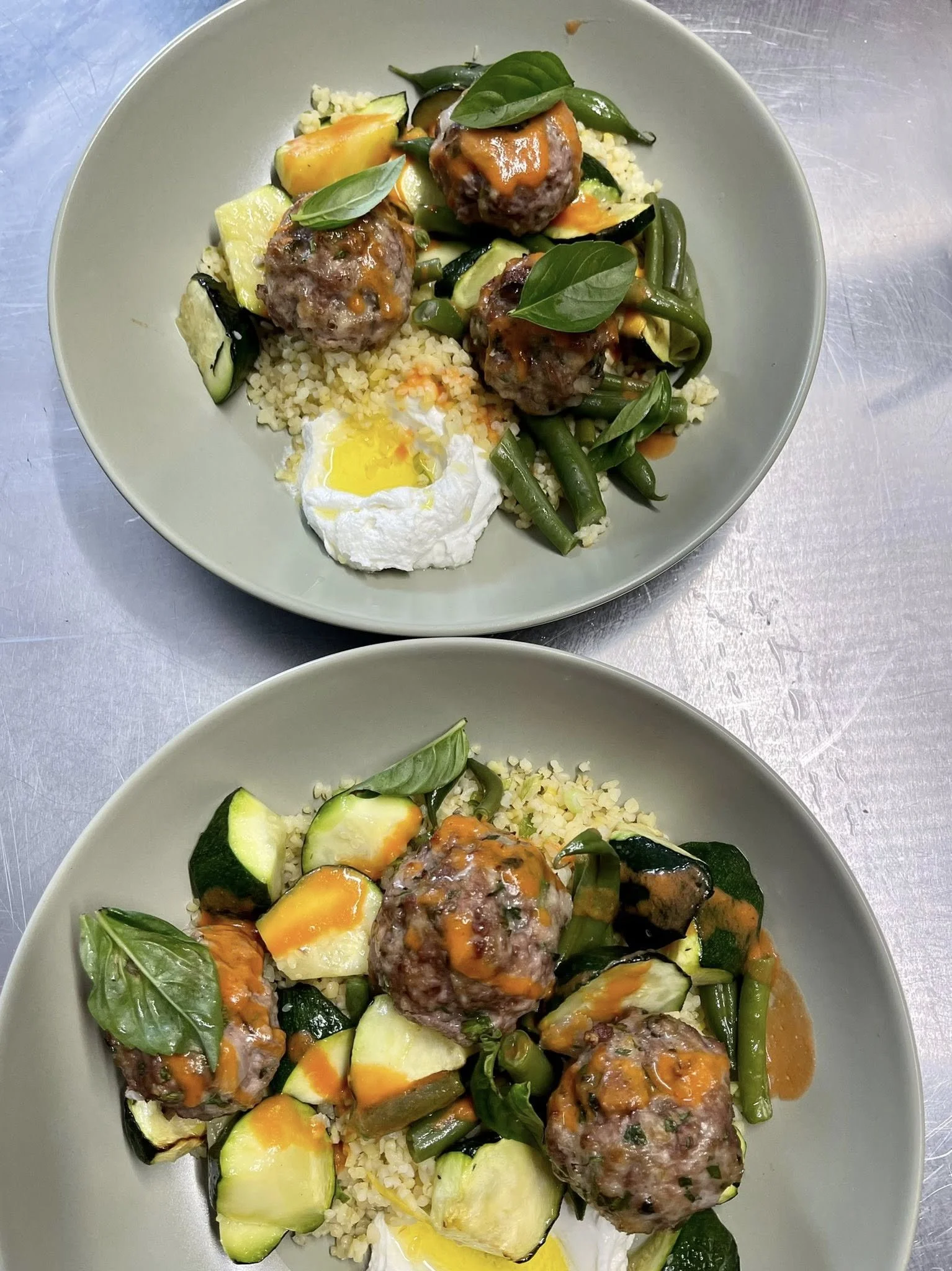 Plate de viande hachée en boulettes servie avec des légumes, un œuf cuit mollet, du riz et des feuilles de basilic