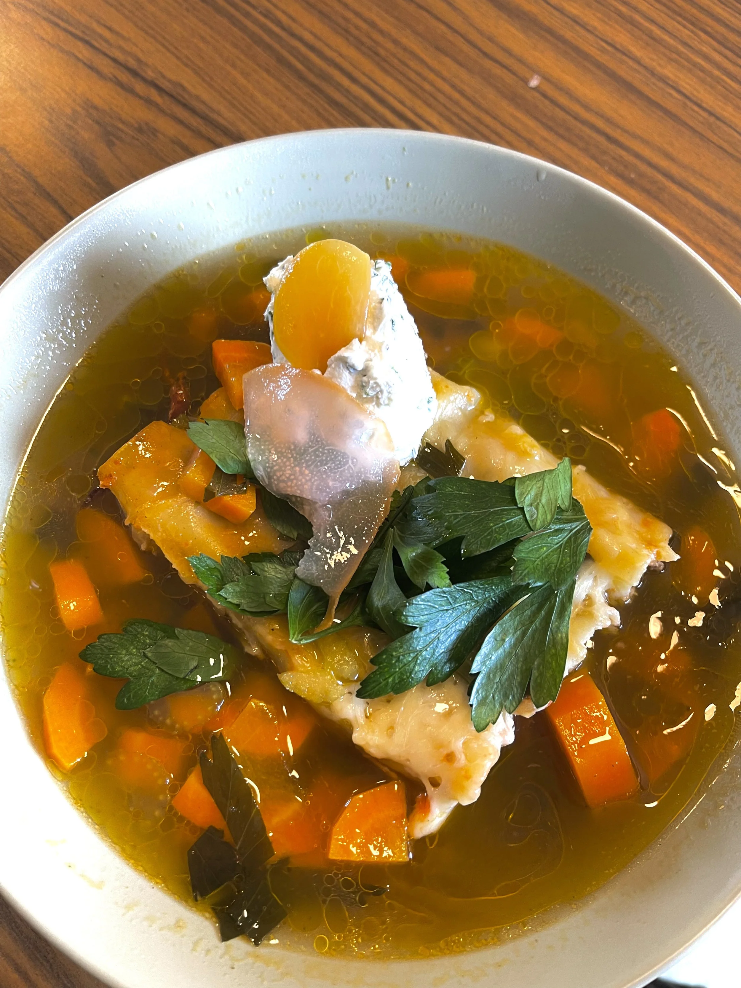Soupe claire avec des morceaux de légumes, garnie de persil frais