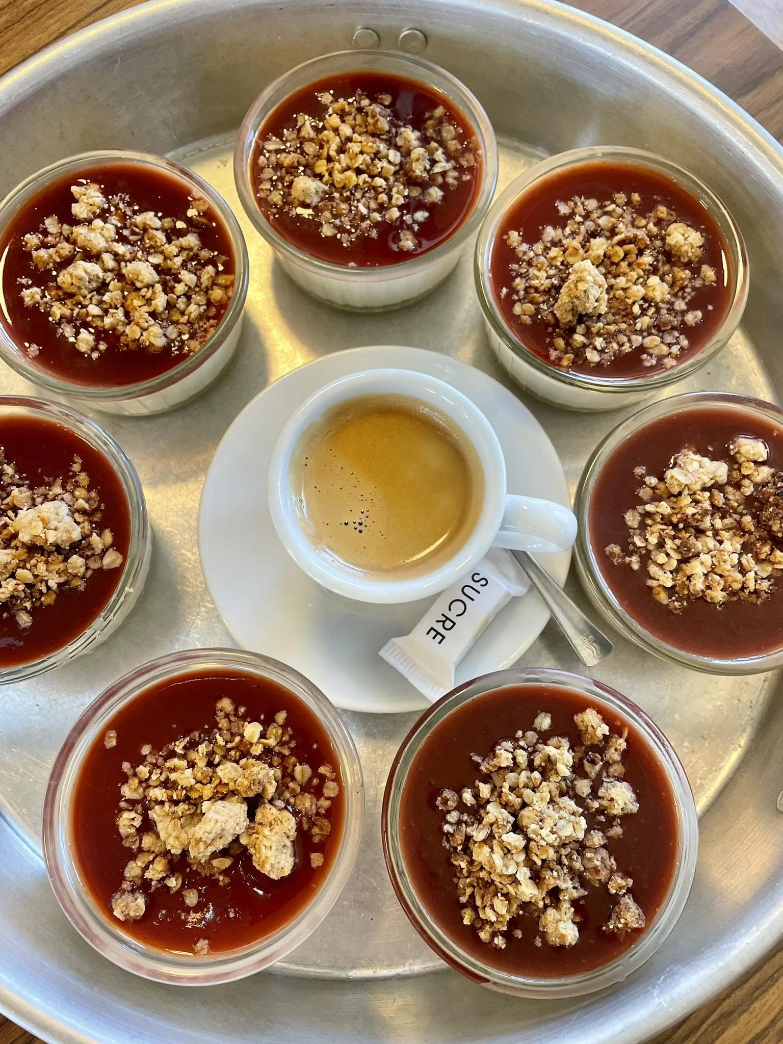 Crèmes caramel à la vanille garnies d'amandes effilées, servies dans des petits ramequins en verre, avec une tasse de café expresso à côté.