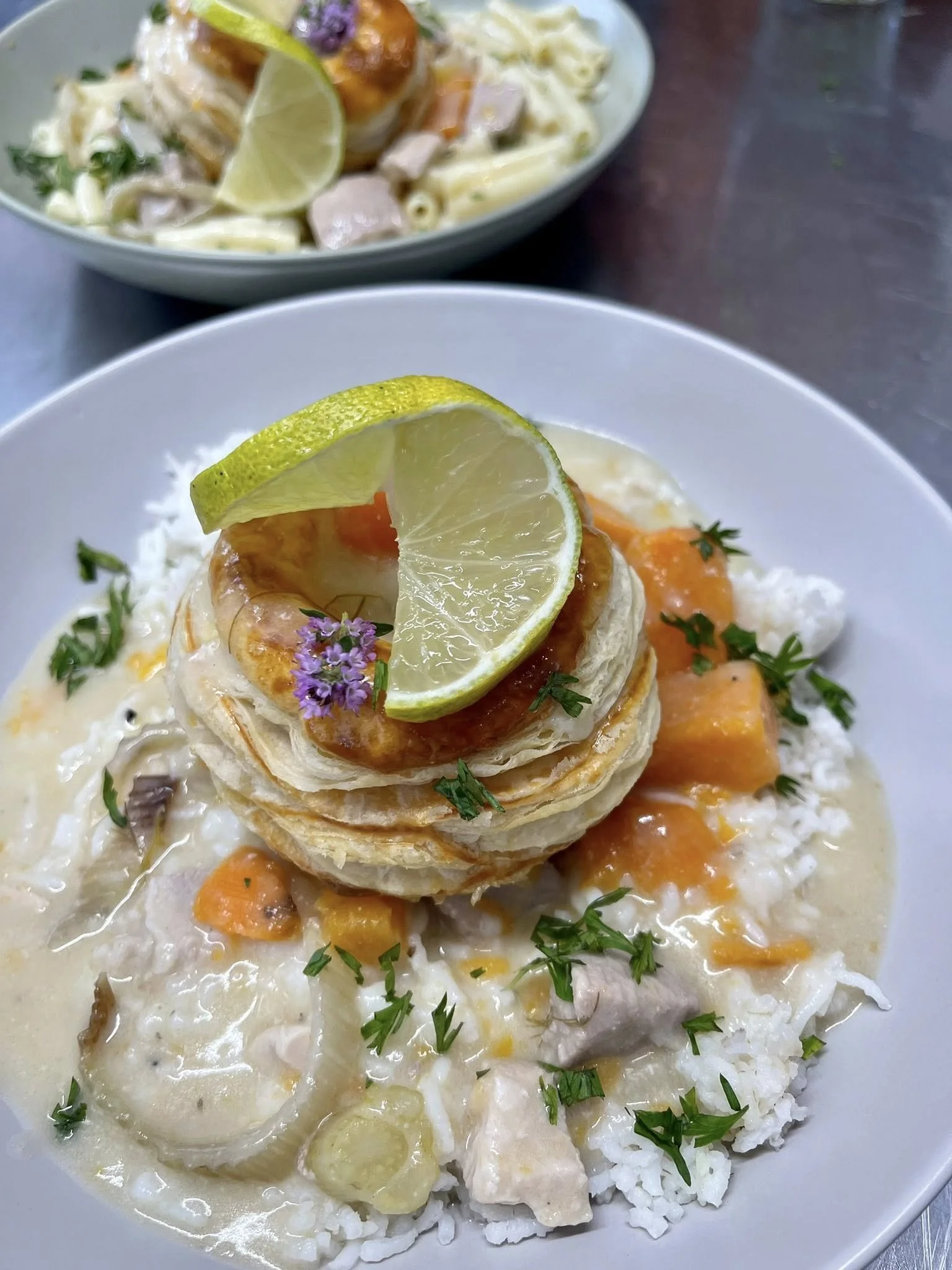 Assiette de riz avec poulet, légumes, et une tourte feuilletée garnie de citron, ail, et herbes, accompagnée de sauce blanche.