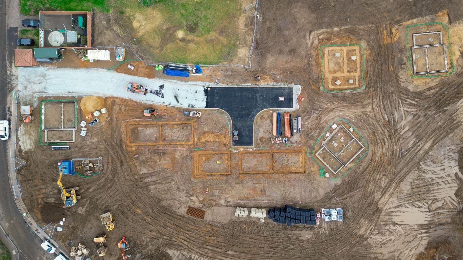  aerial view of a construction site with various building foundations, construction vehicles, and materials.