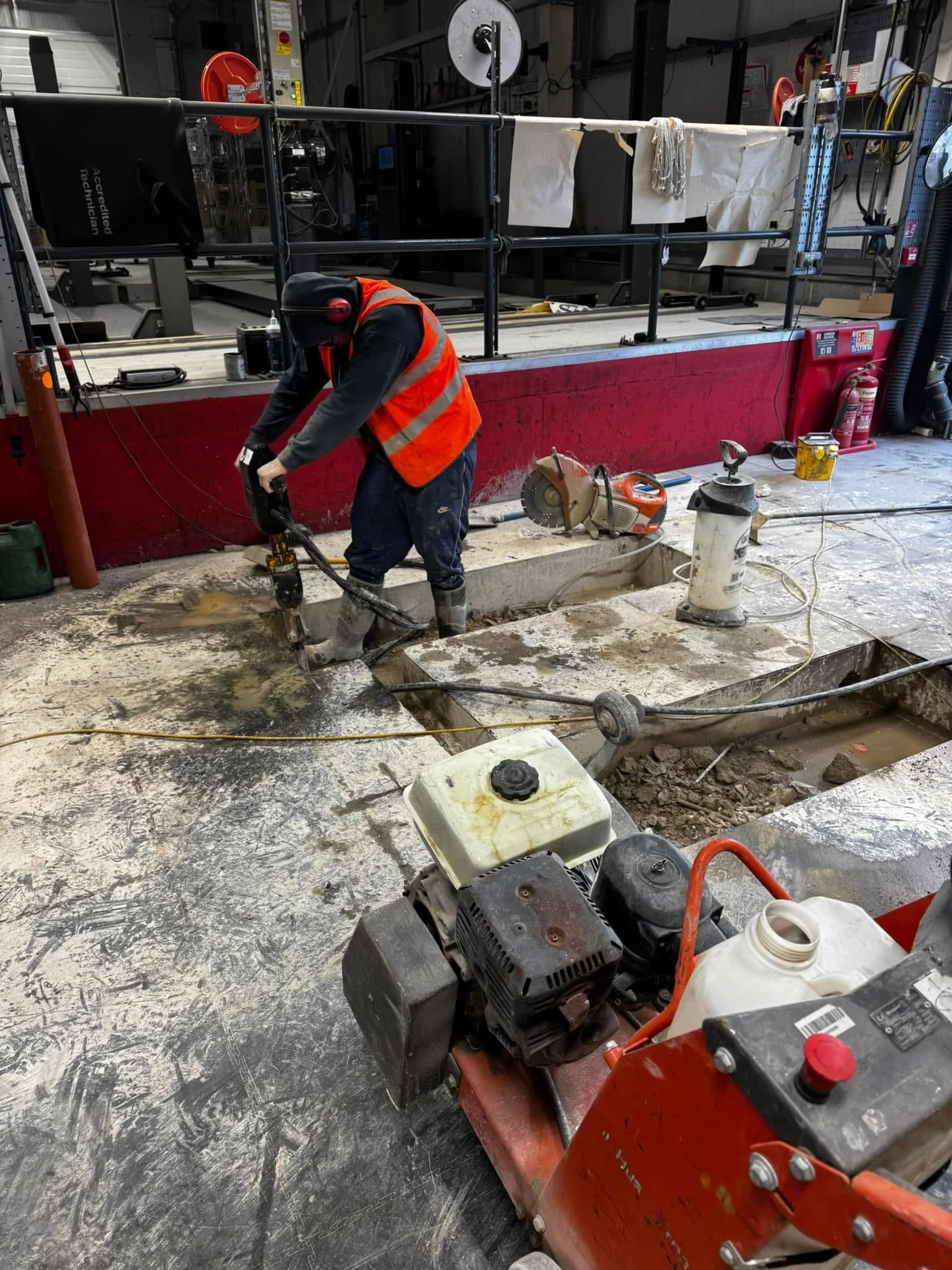 Worker in safety gear using a handheld power tool to install a new garage lift bay