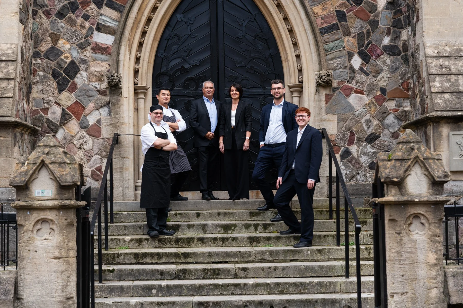 the spiros team smiling on the steps outside cornerstone cardiff