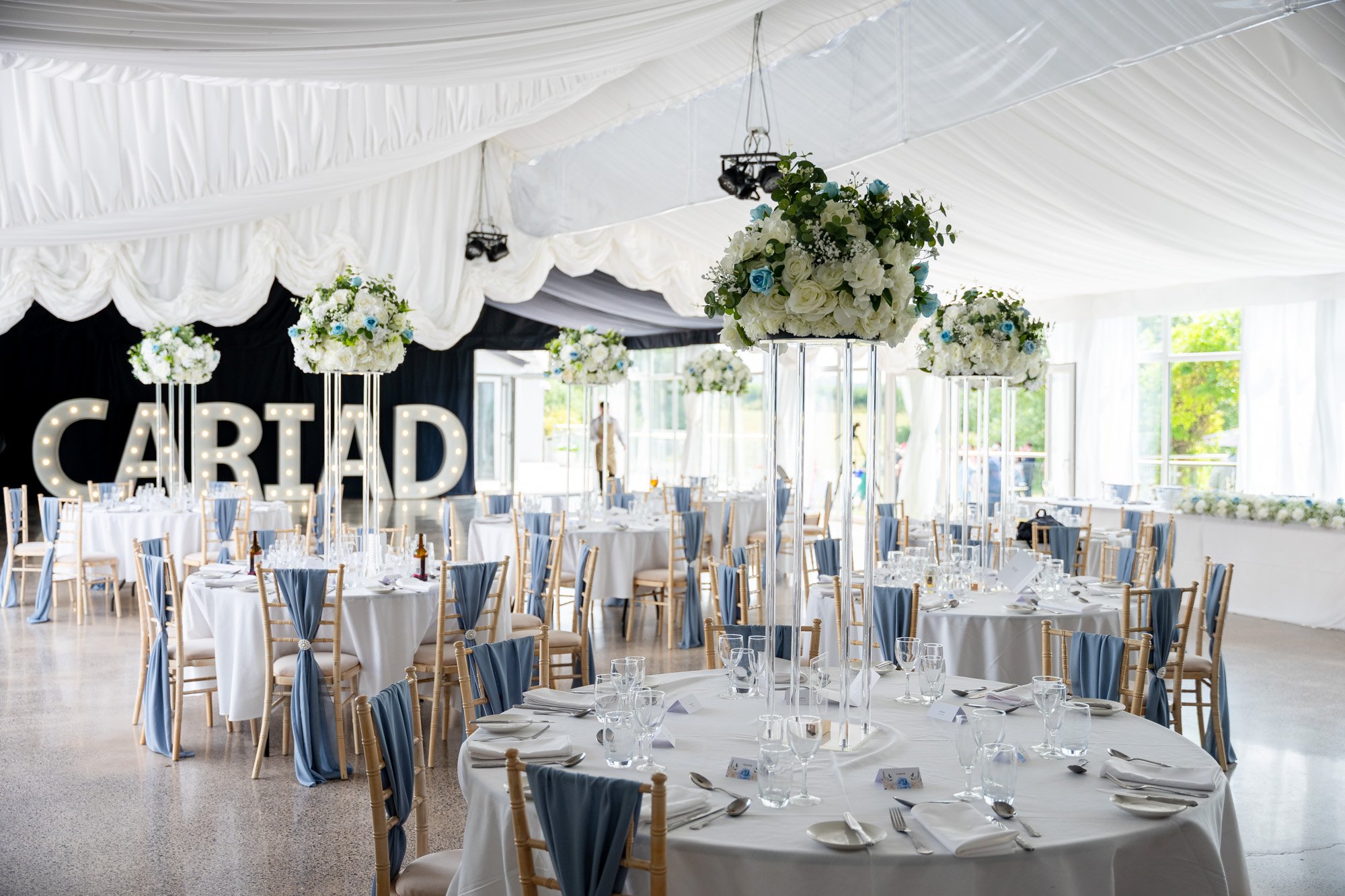 the inside of a beautifully decorated marquee at dyffryn springs with light up letters spelling cariad