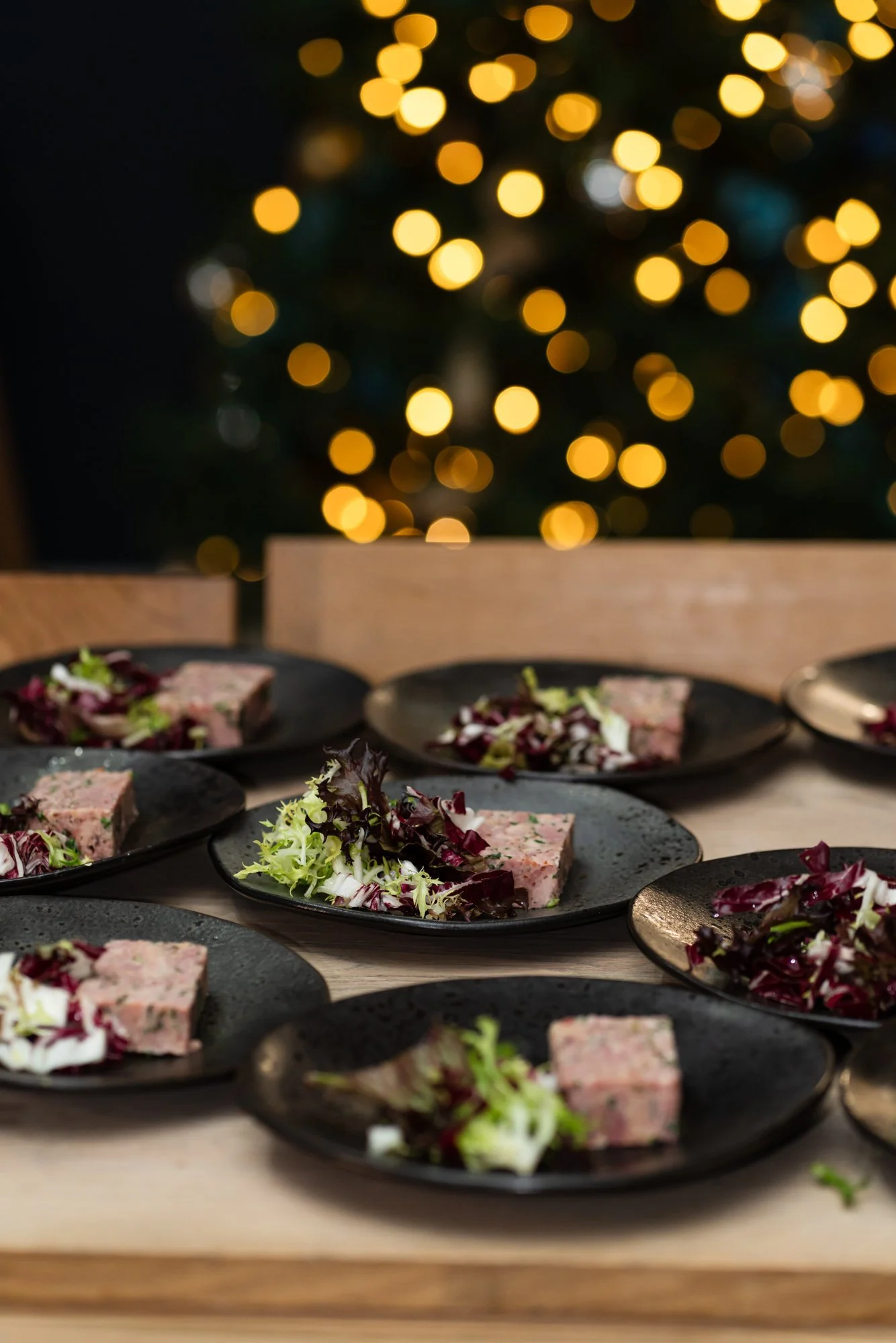 plates of pate and garnish in front of cosy bokka lights in the background